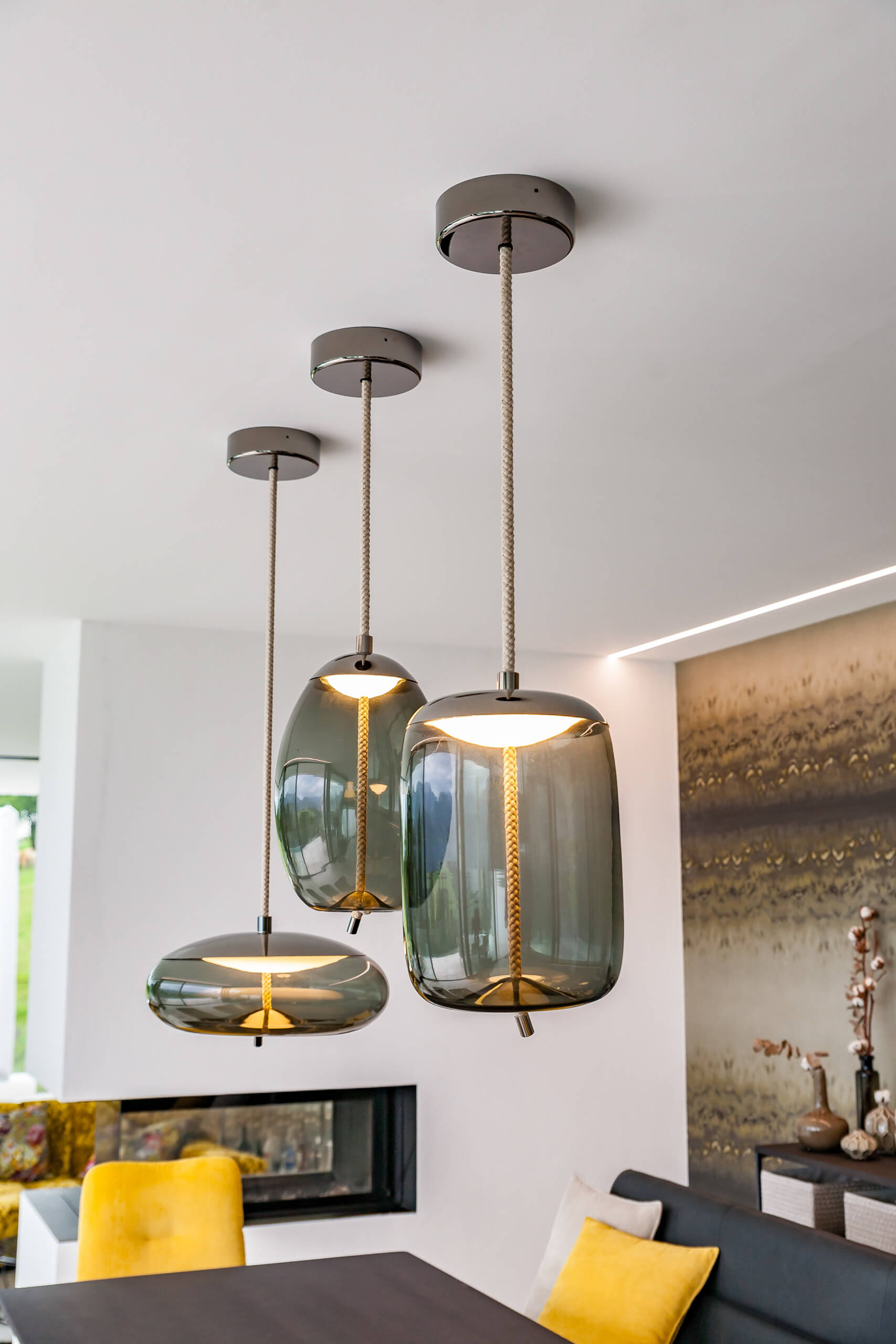 Moderne Hängeleuchten aus Glas über einem Kamin – Lichtplanung von Illumina.