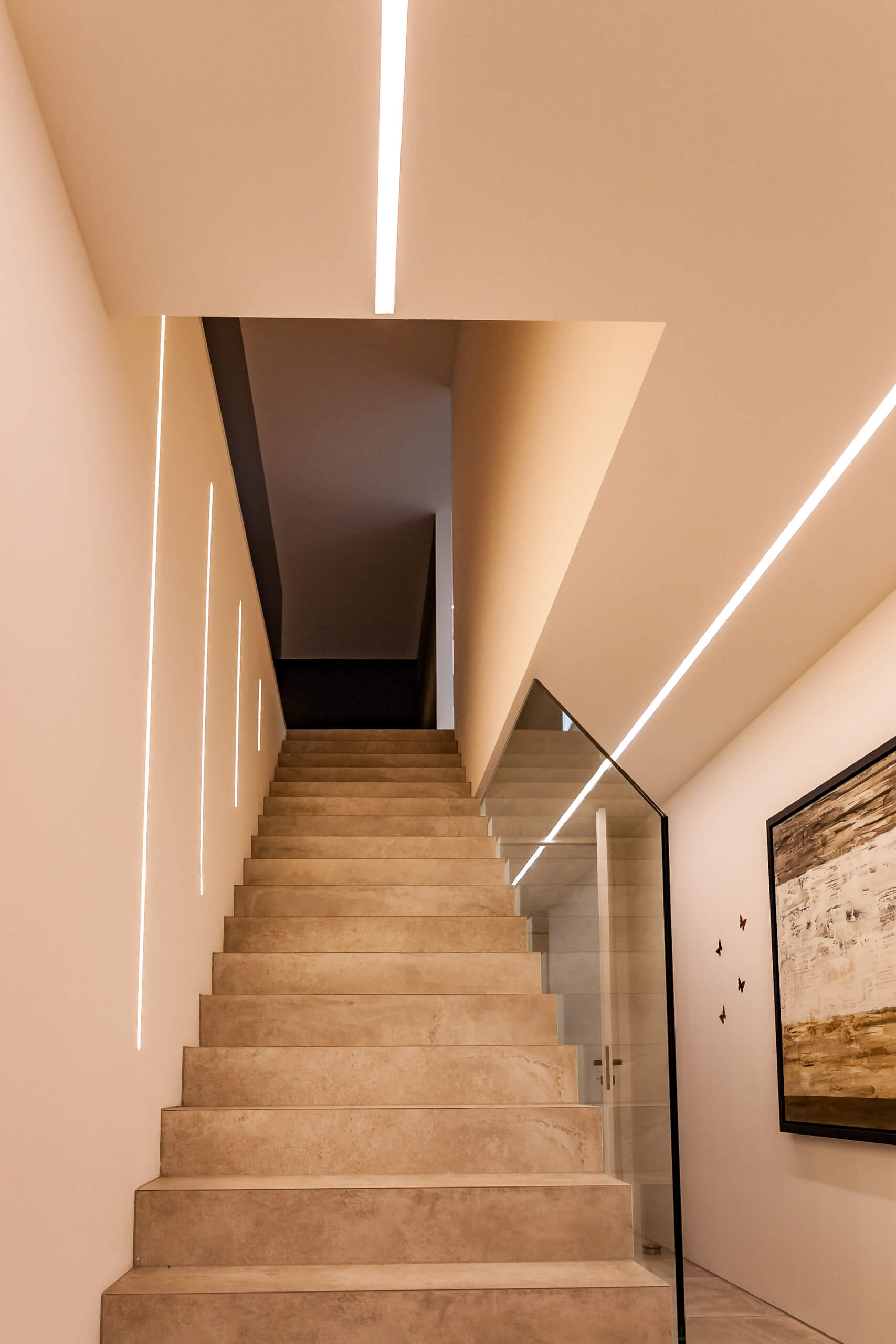 Moderne Treppe mit indirekter Beleuchtung und Glasgeländer – Lichtplanung von Illumina