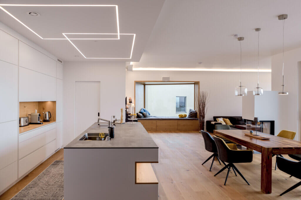 Moderne Wohnküche mit Essbereich und Kamin – Lichtplanung von Illumina.