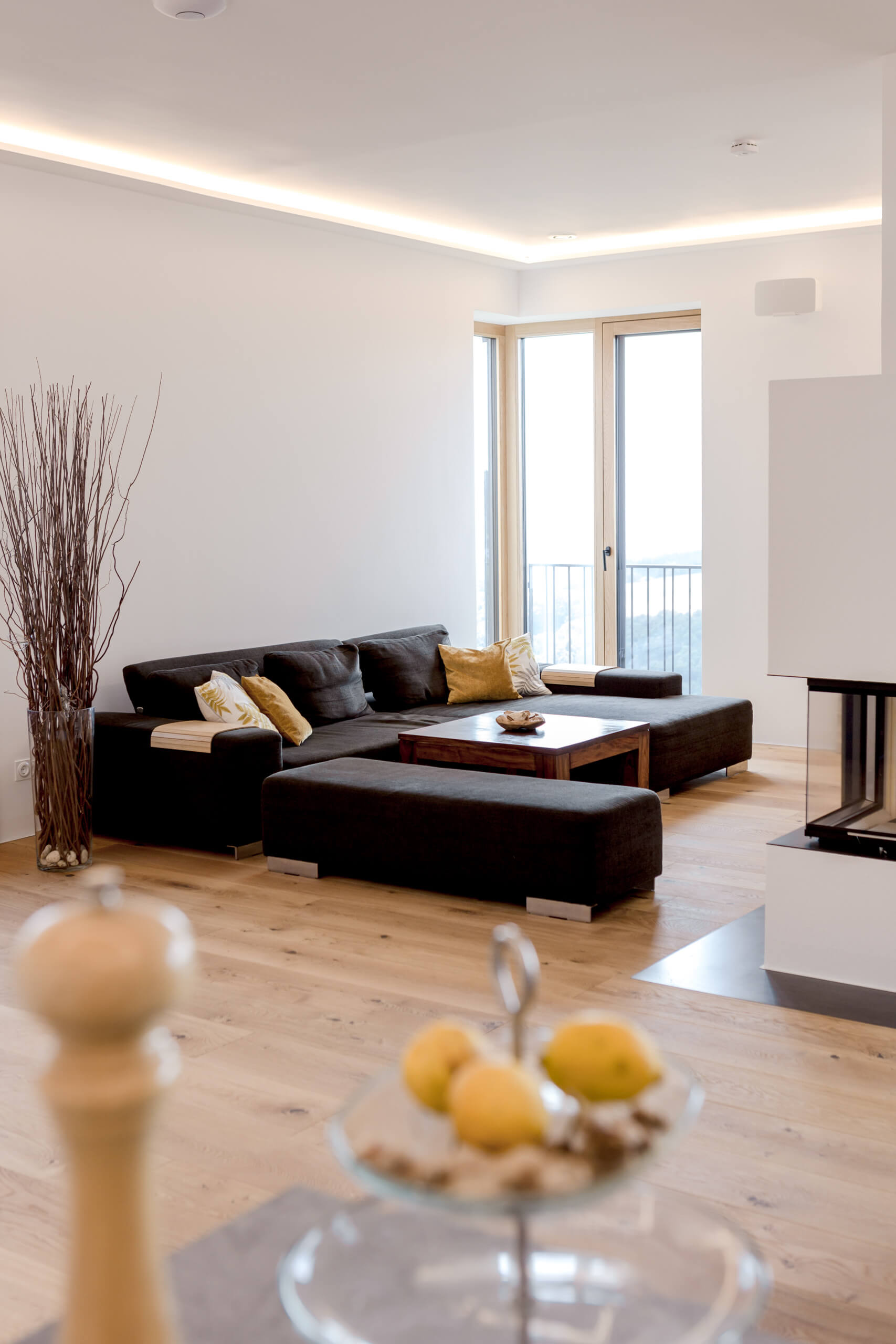 Modernes Wohnzimmer mit dunklem Ecksofa und indirekter Beleuchtung.