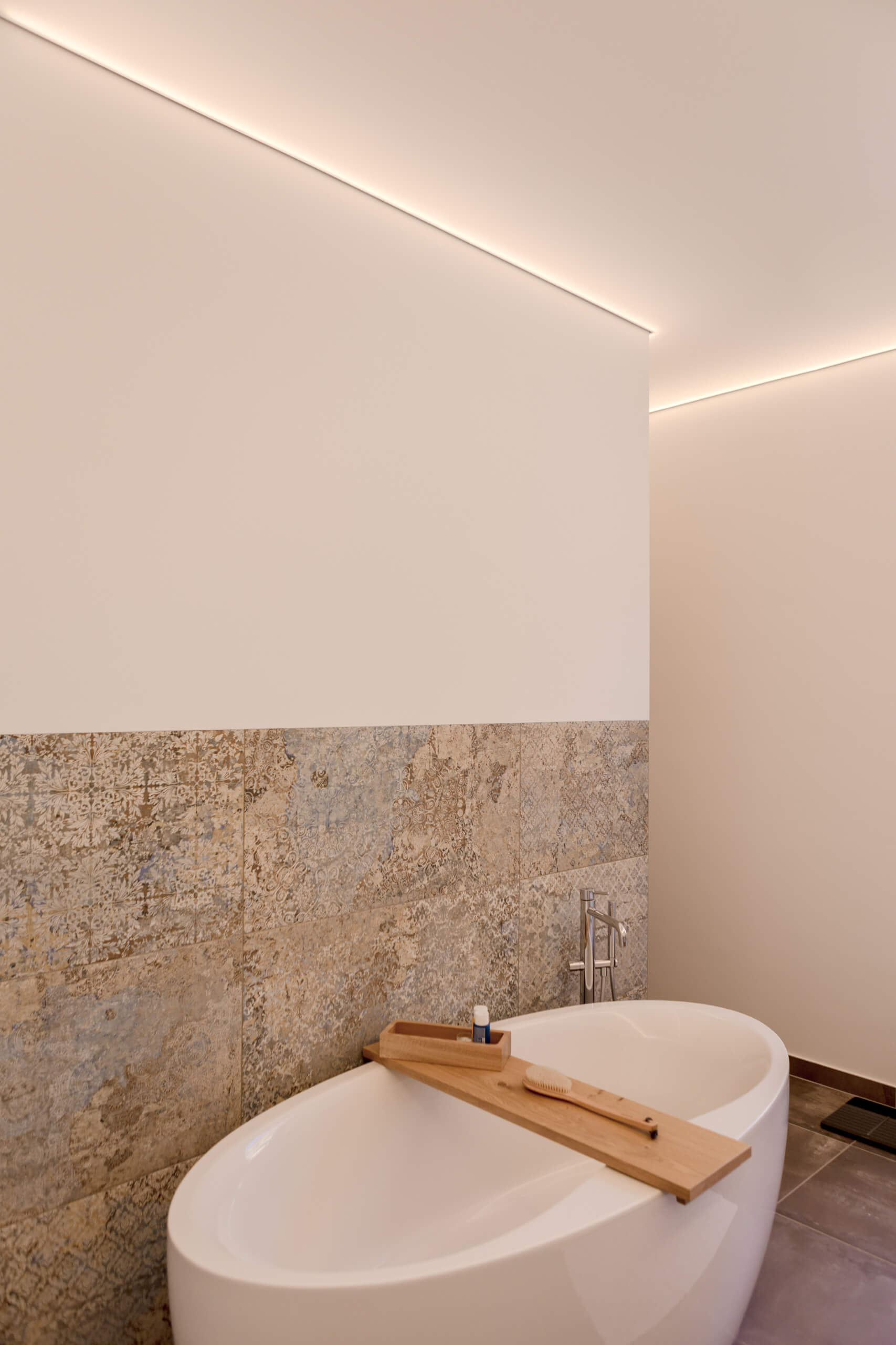 Elegante freistehende Badewanne mit Holzbadebrett und indirekter Beleuchtung