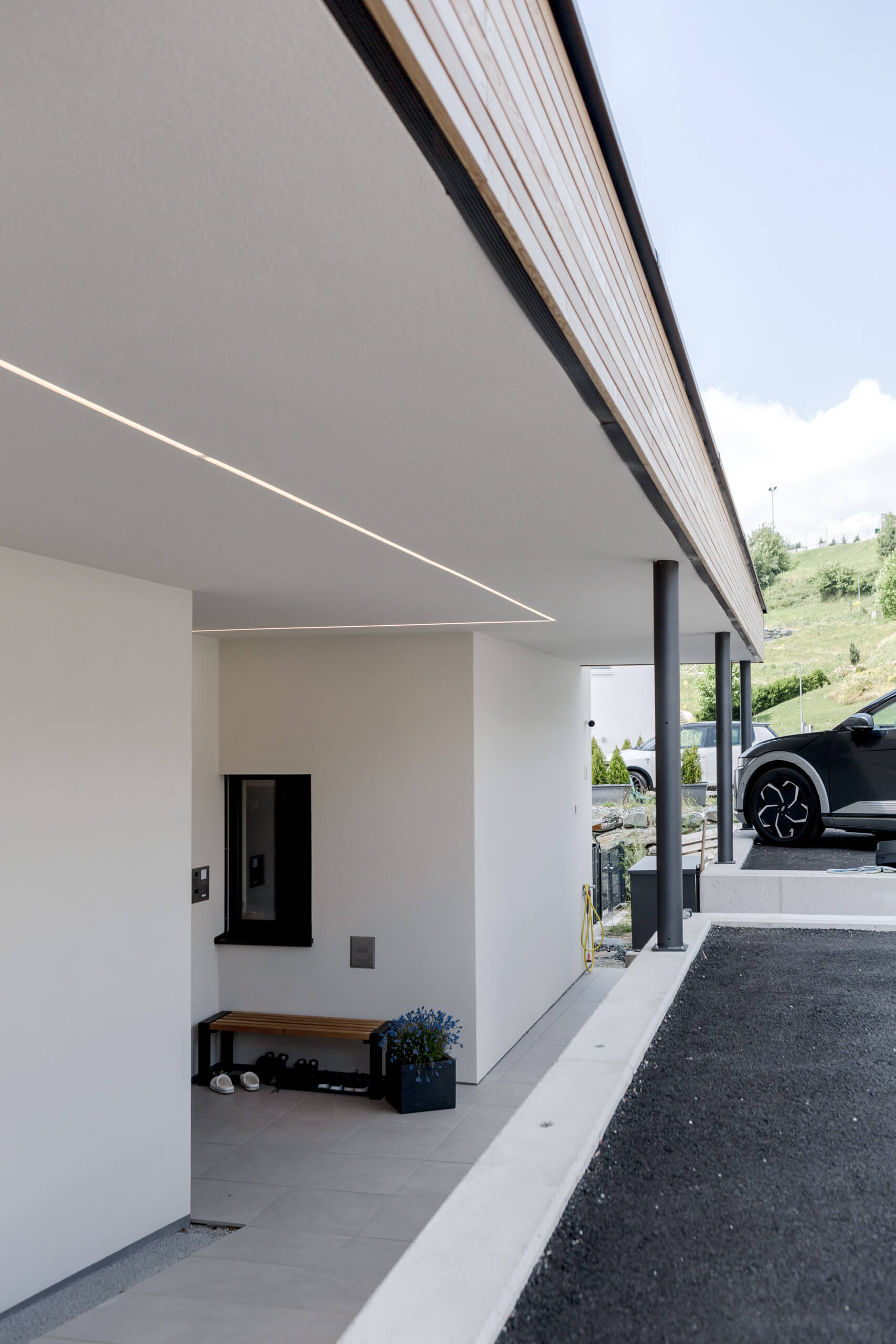 Moderne Hauszufahrt mit Überdachung und indirekter Beleuchtung – Lichtplanung von Illumina.