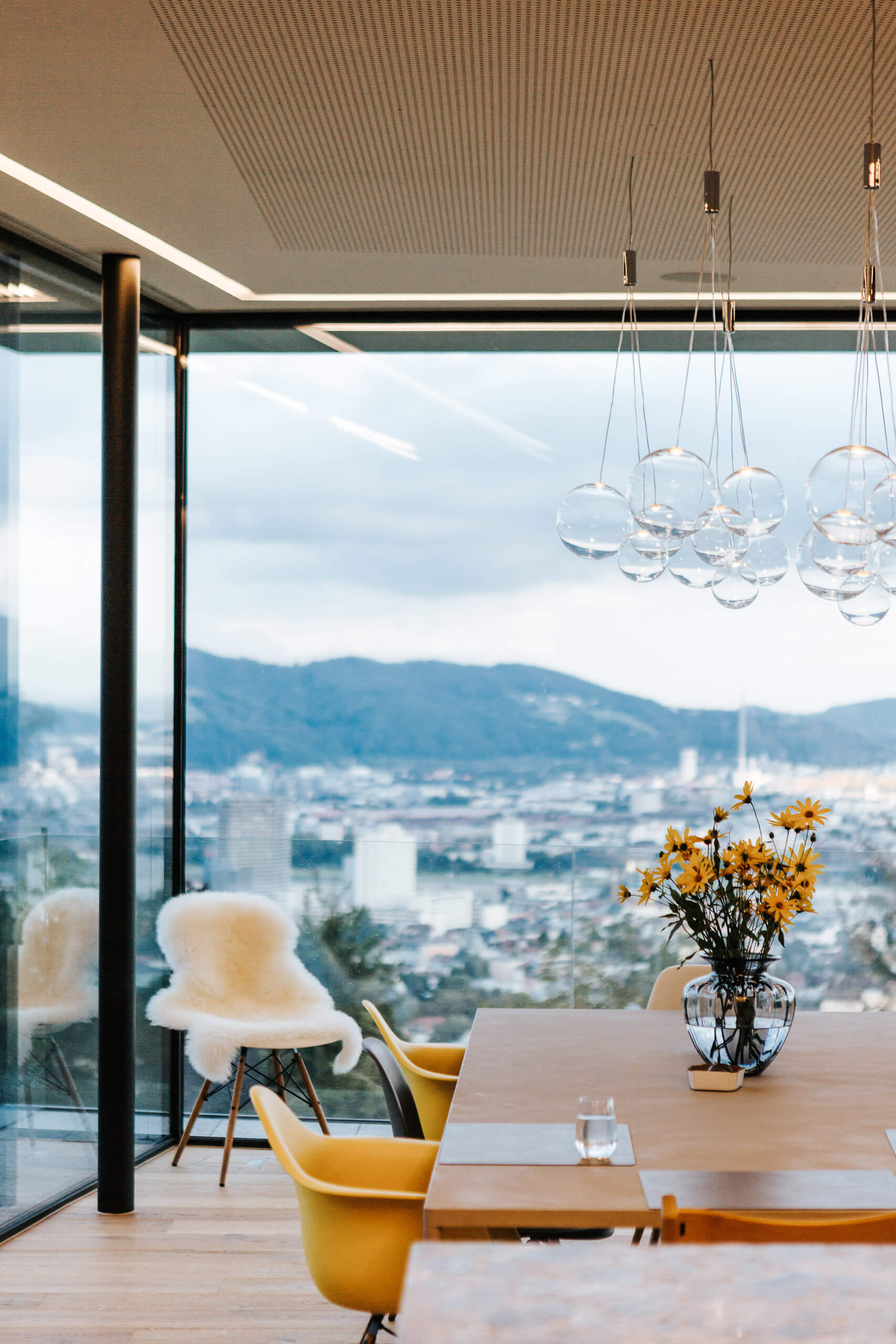 Modernes Esszimmer mit Panoramablick und stilvollen Hängeleuchten von Illumina.