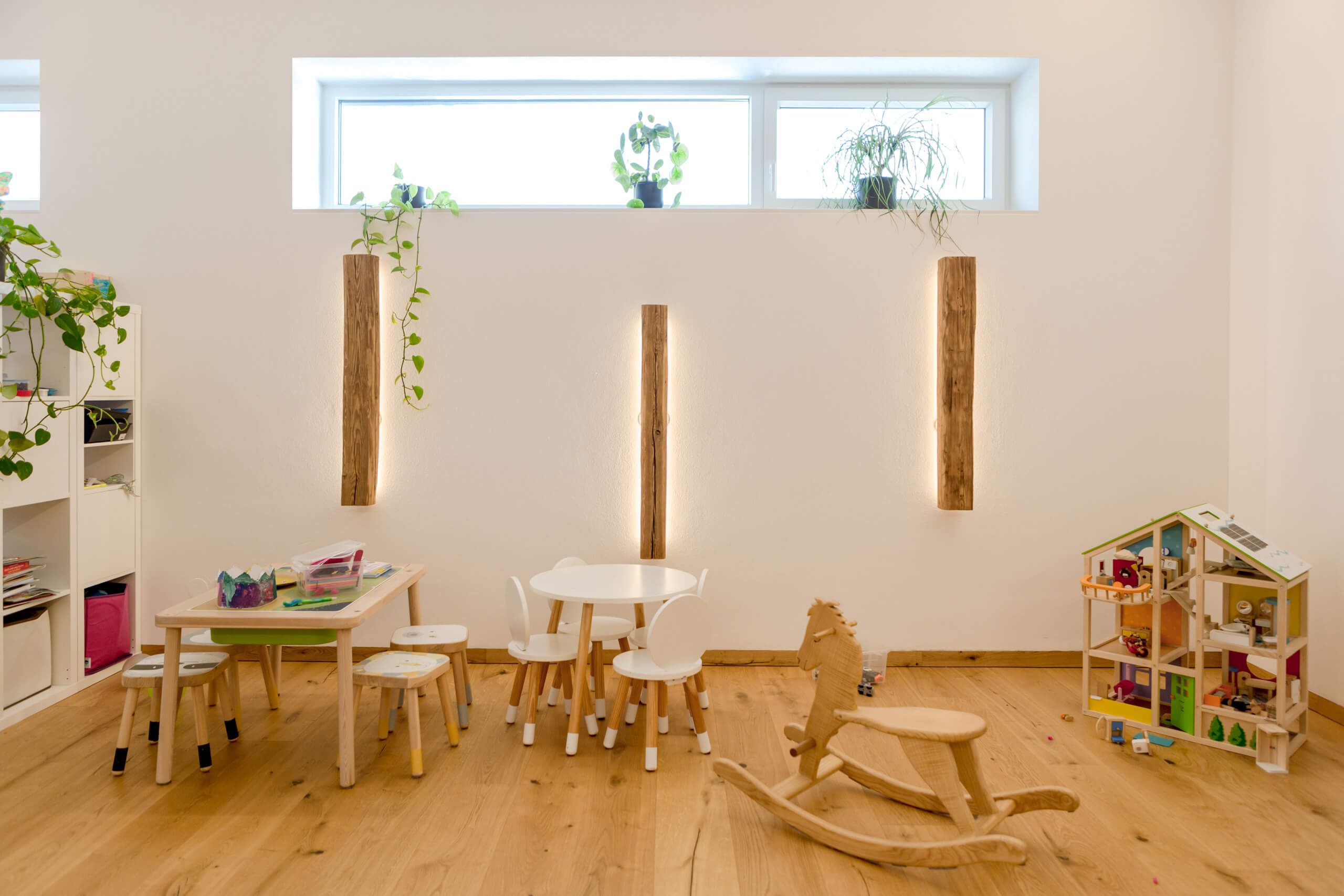 Kinderzimmer mit Spieltisch und Holzspielzeug, beleuchtet durch indirektes Licht.