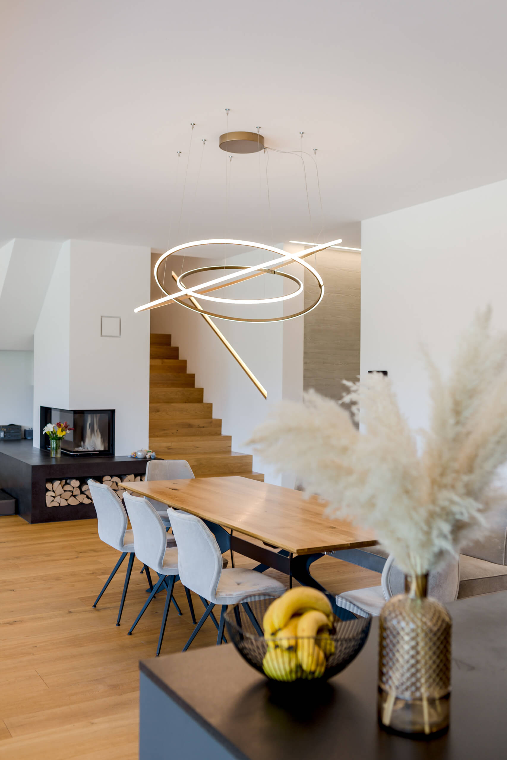 Modernes Esszimmer mit Esstisch, Stühlen und Kamin – Lichtplanung von Illumina.