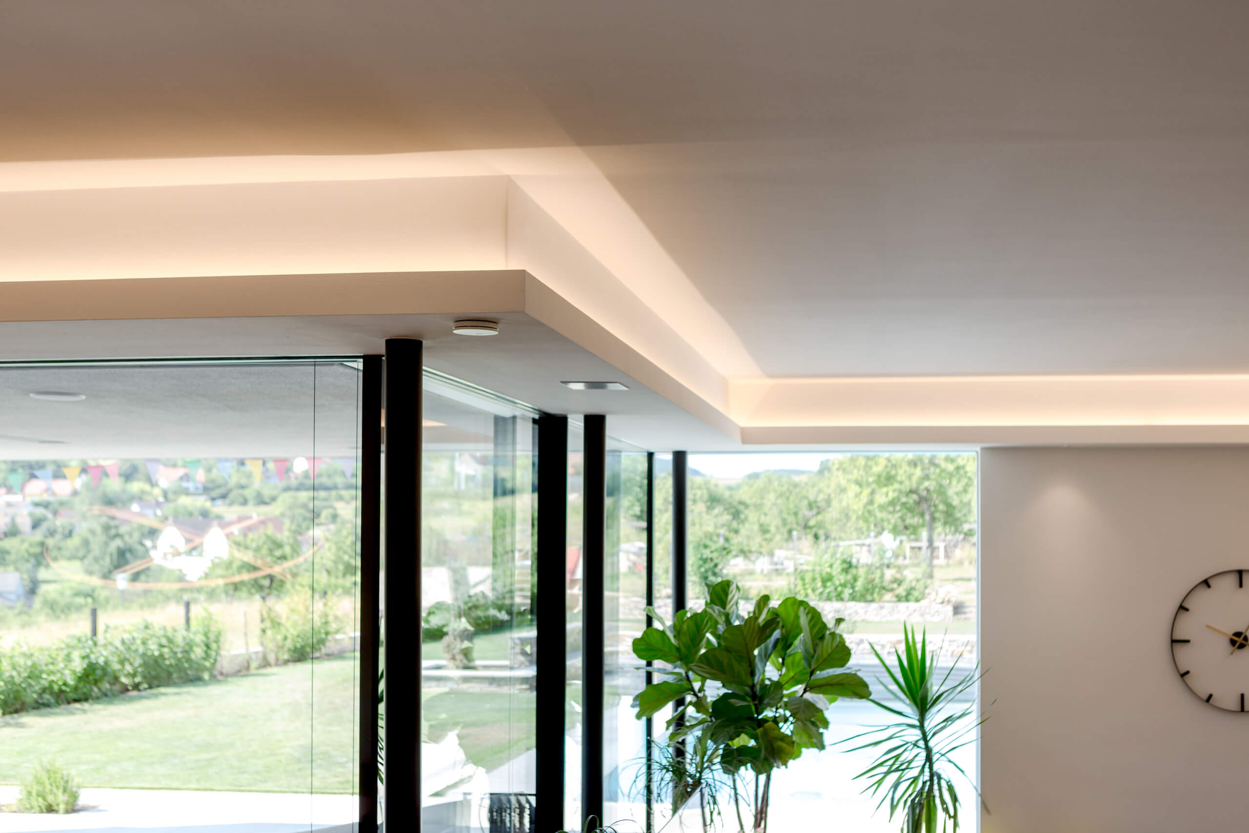 Moderne Deckenbeleuchtung mit indirektem Licht und Pflanzen im Innenraum
