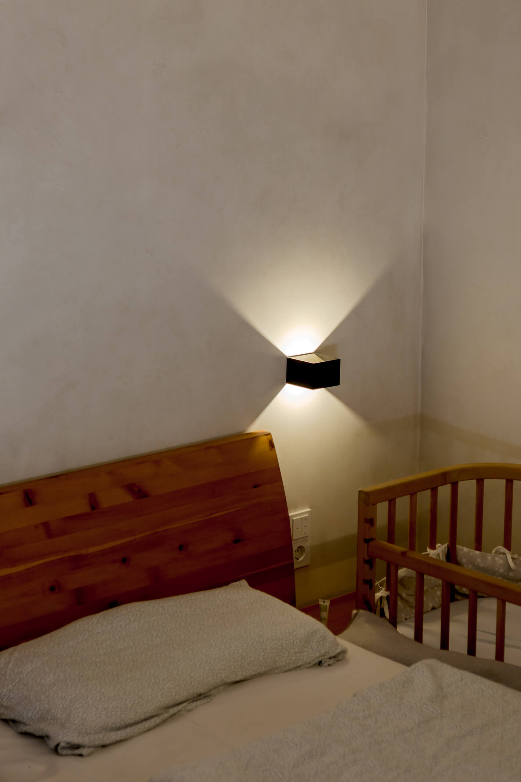 Schlafzimmer mit Kinderbett und moderner Wandleuchte – Lichtplanung von Illumina.