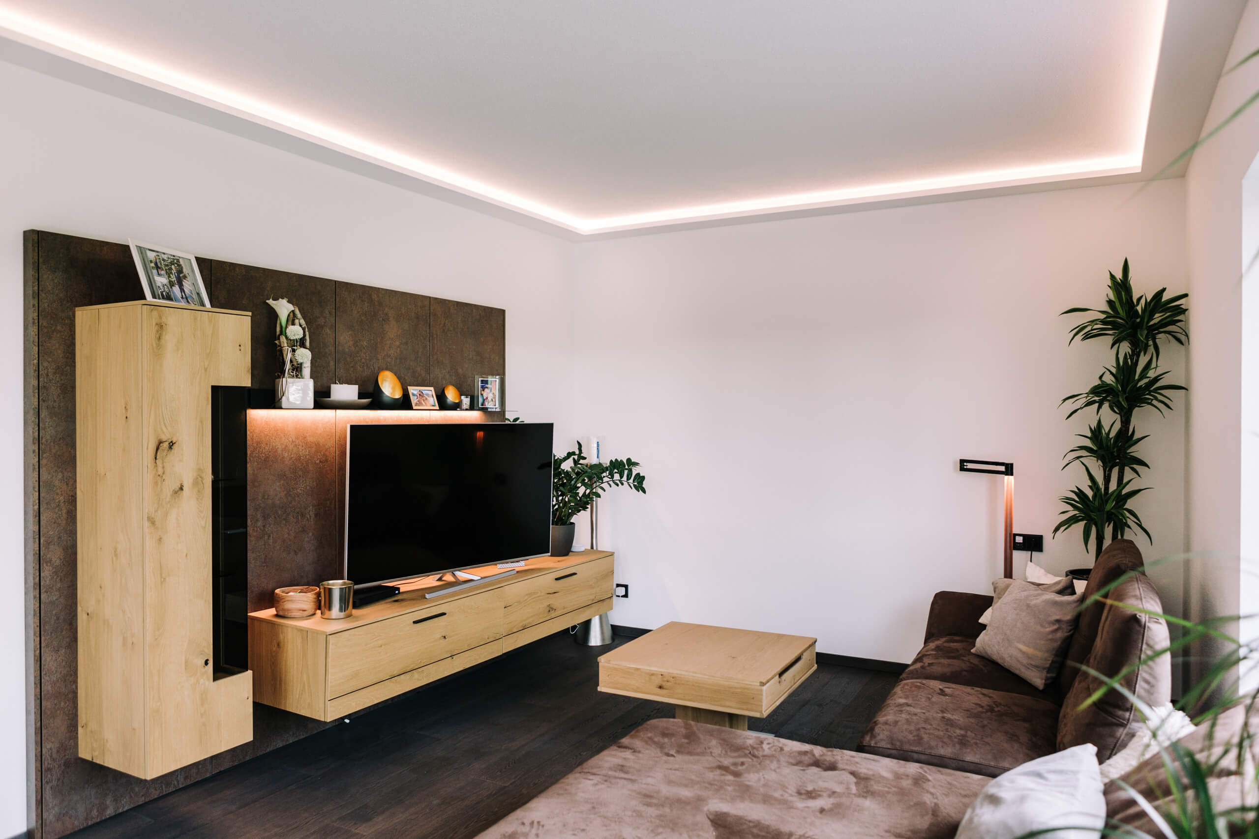 Modernes Wohnzimmer mit indirekter Beleuchtung und brauner Ledercouch.