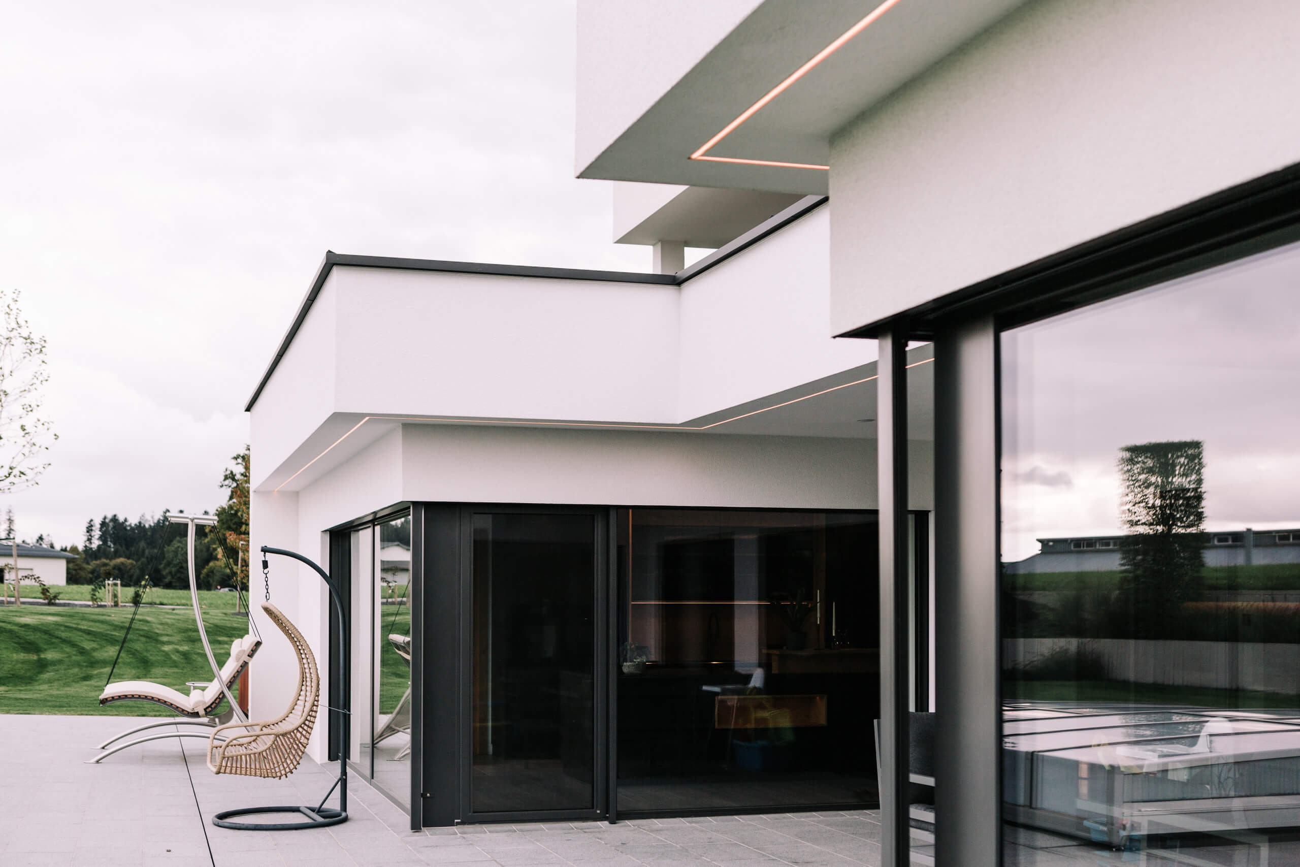 Moderne Architektur mit Akzentbeleuchtung und Außensitzbereich – Lichtplanung von Illumina.