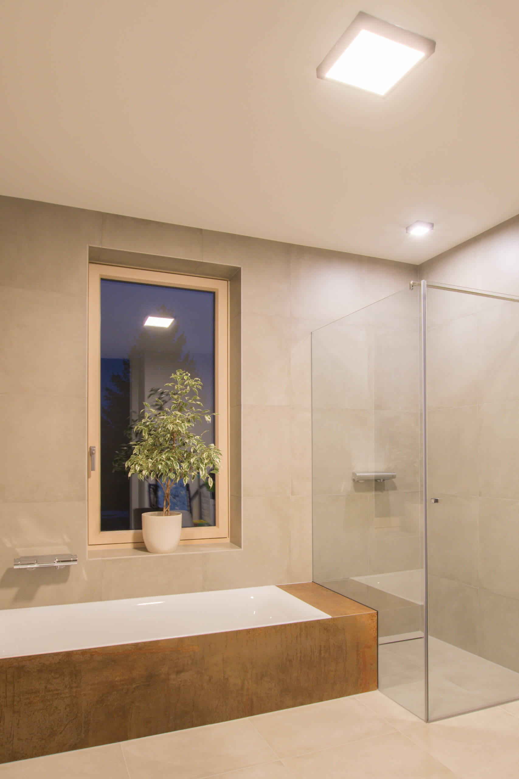 Modernes Badezimmer mit Badewanne, Duschkabine und Fenster mit Pflanze