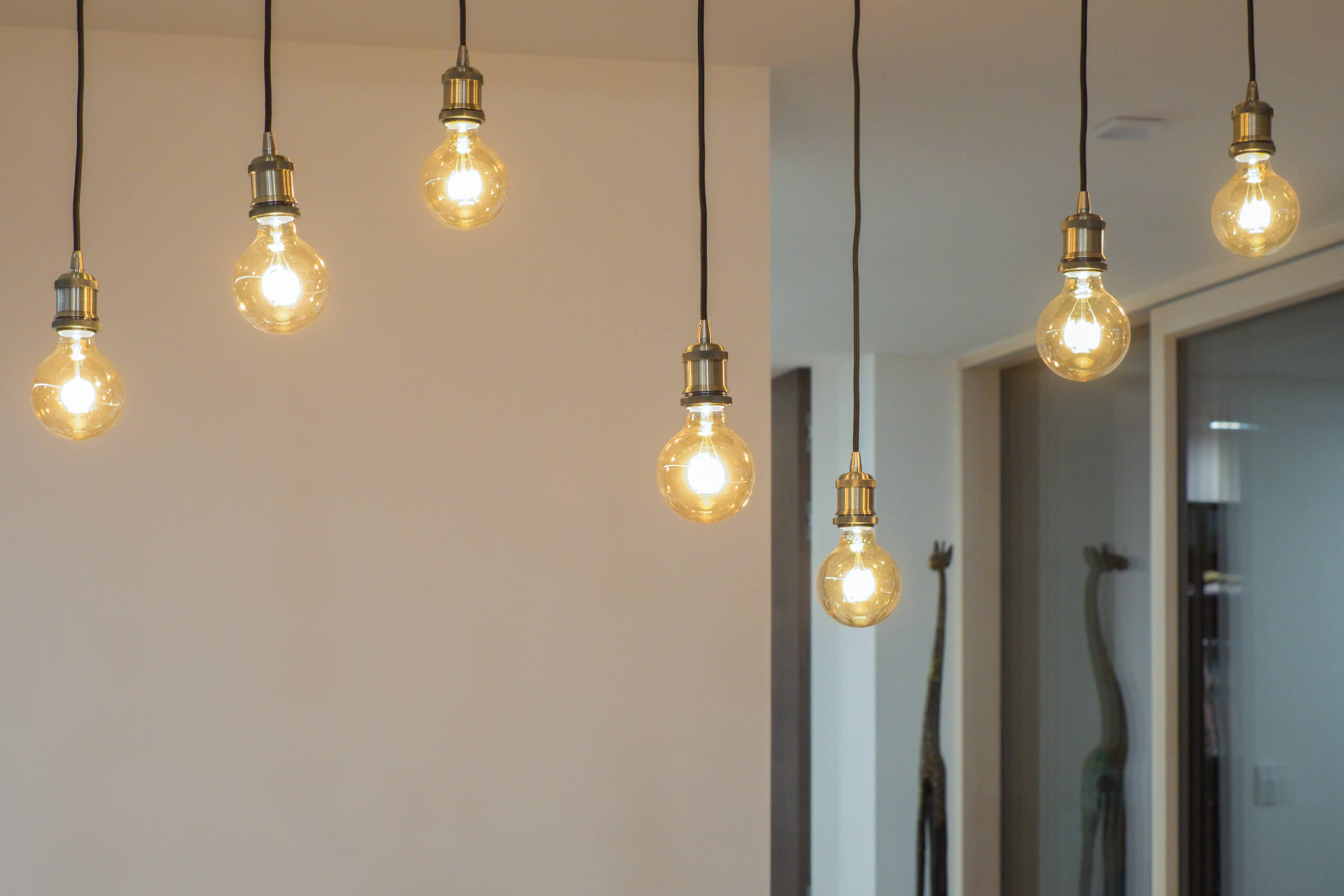 Moderne Hängeleuchten mit Glühfaden-Optik in hellem Raum – Lichtplanung von Illumina.