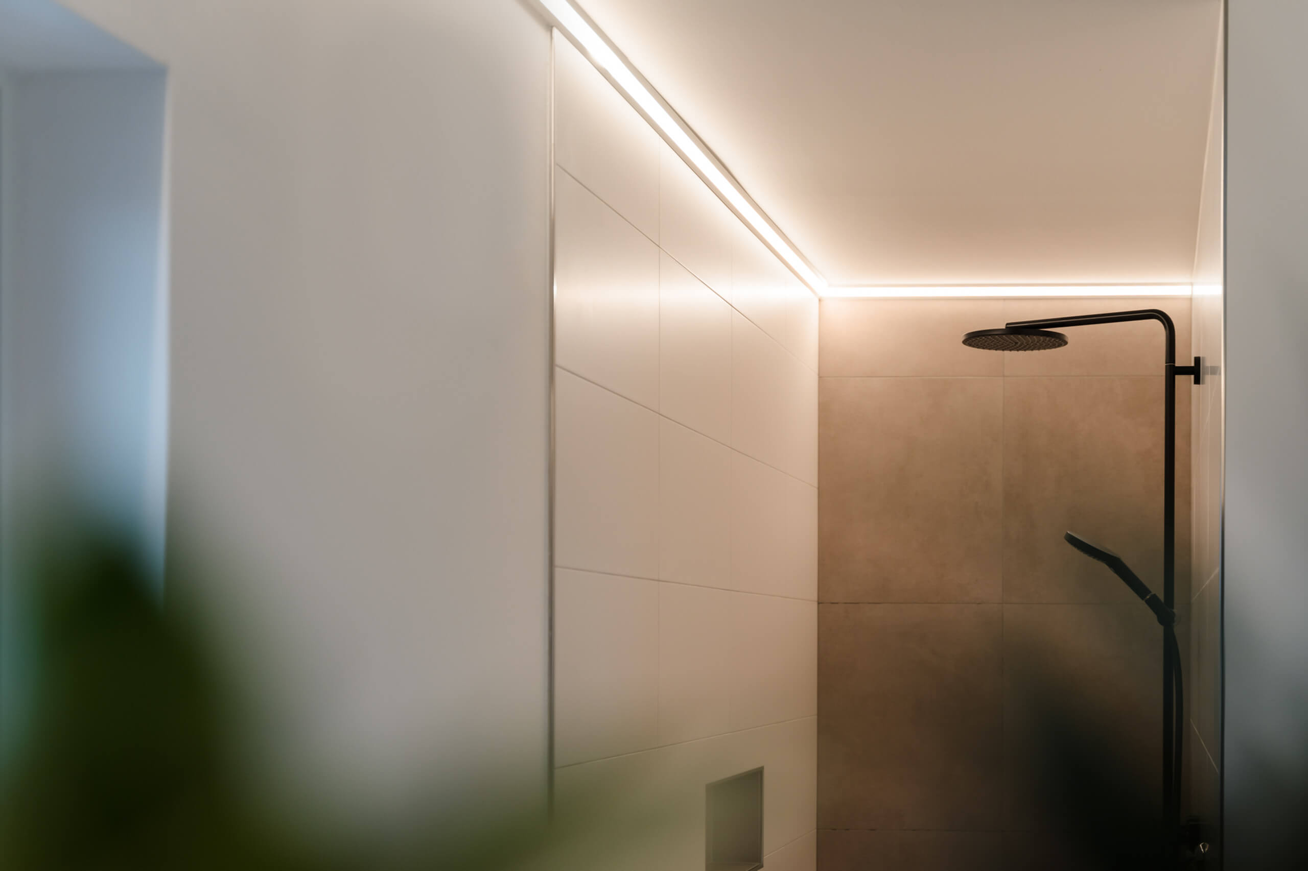 Moderne Duschkabine mit indirekter Deckenbeleuchtung und schwarzer Duscharmatur – Lichtplanung von Illumina.
