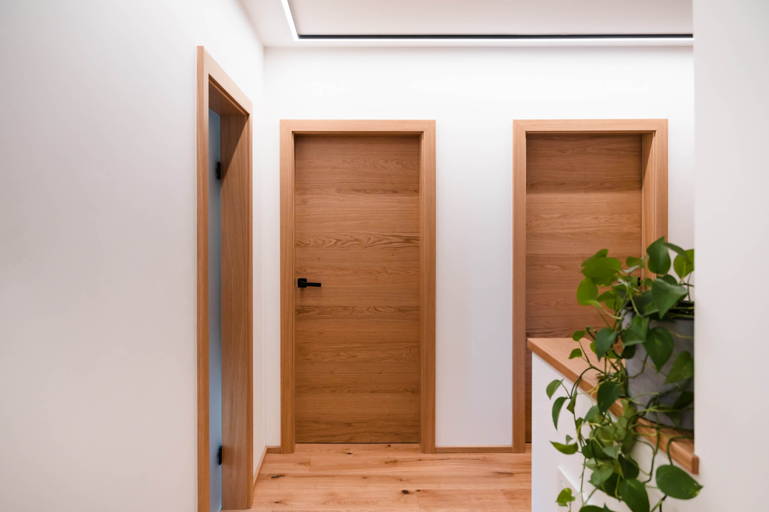Moderne Diele mit Holztüren und dezenter Beleuchtung