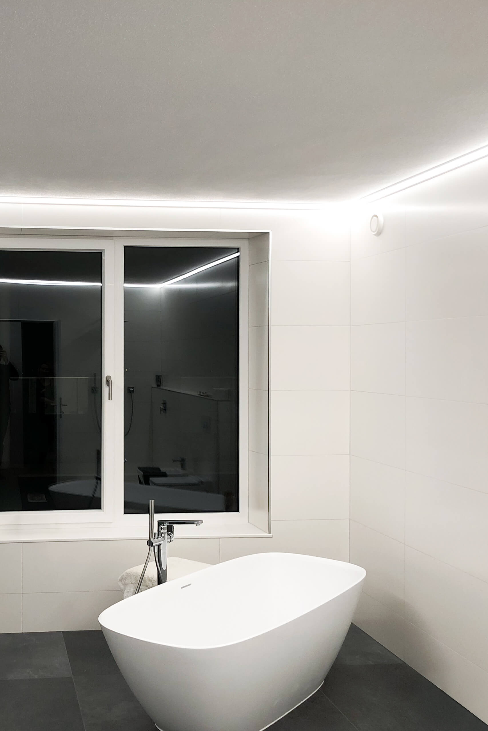 Modernes Badezimmer mit freistehender Badewanne und indirekter Beleuchtung