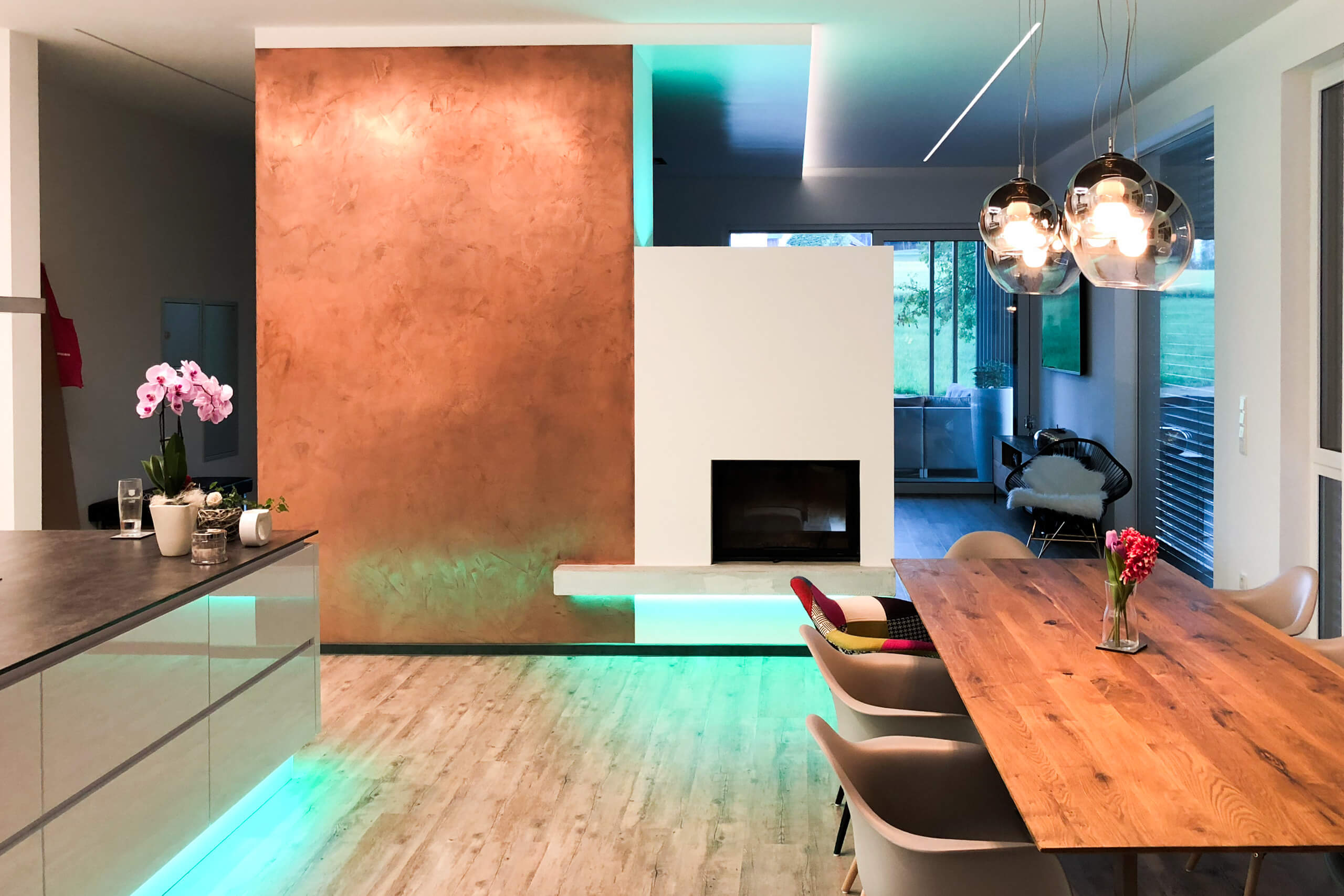 Modernes Esszimmer mit Kamin und kupferfarbener Wand – Lichtplanung von Illumina.