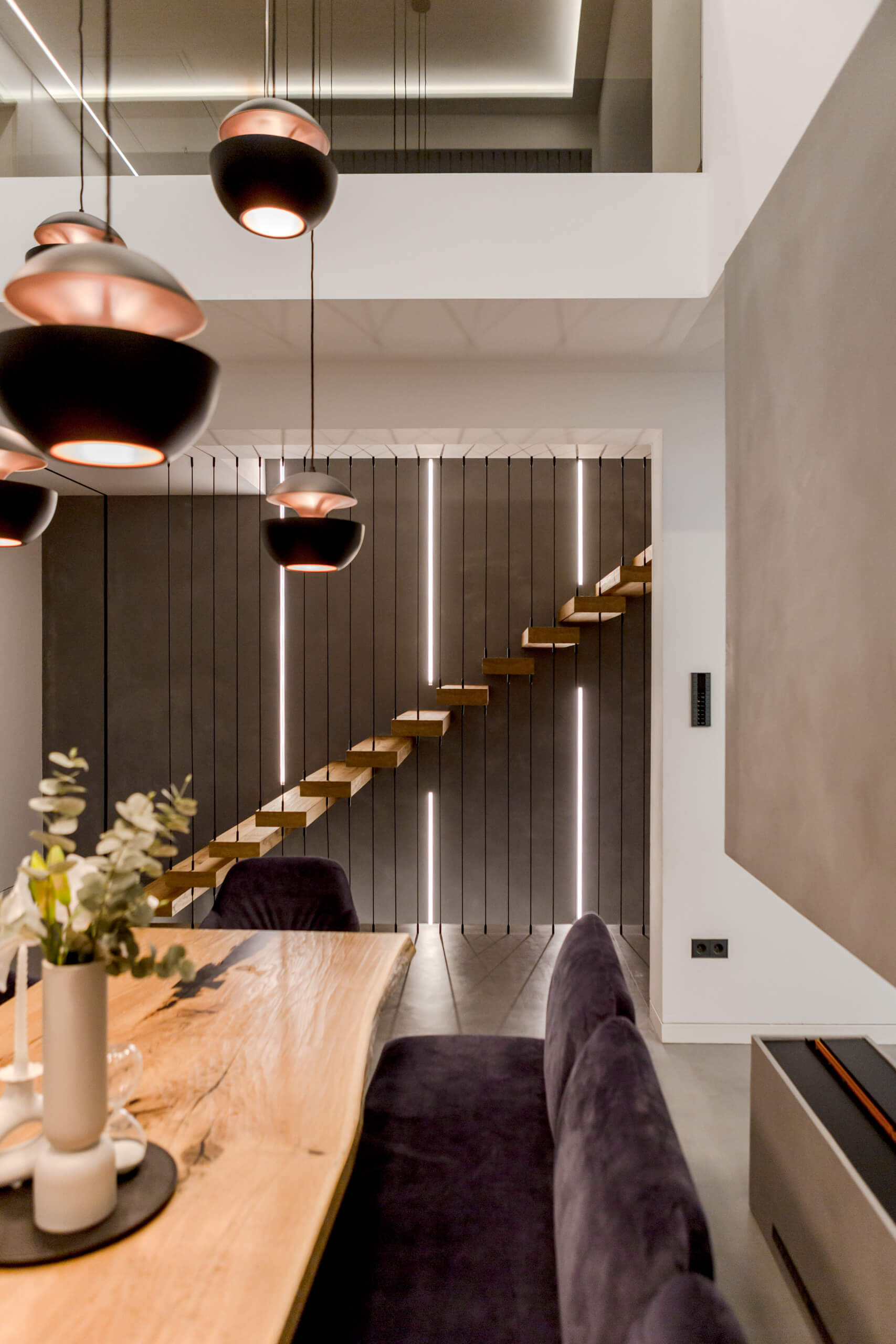 Modernes Esszimmer mit schwebender Holztreppe und Akzentbeleuchtung