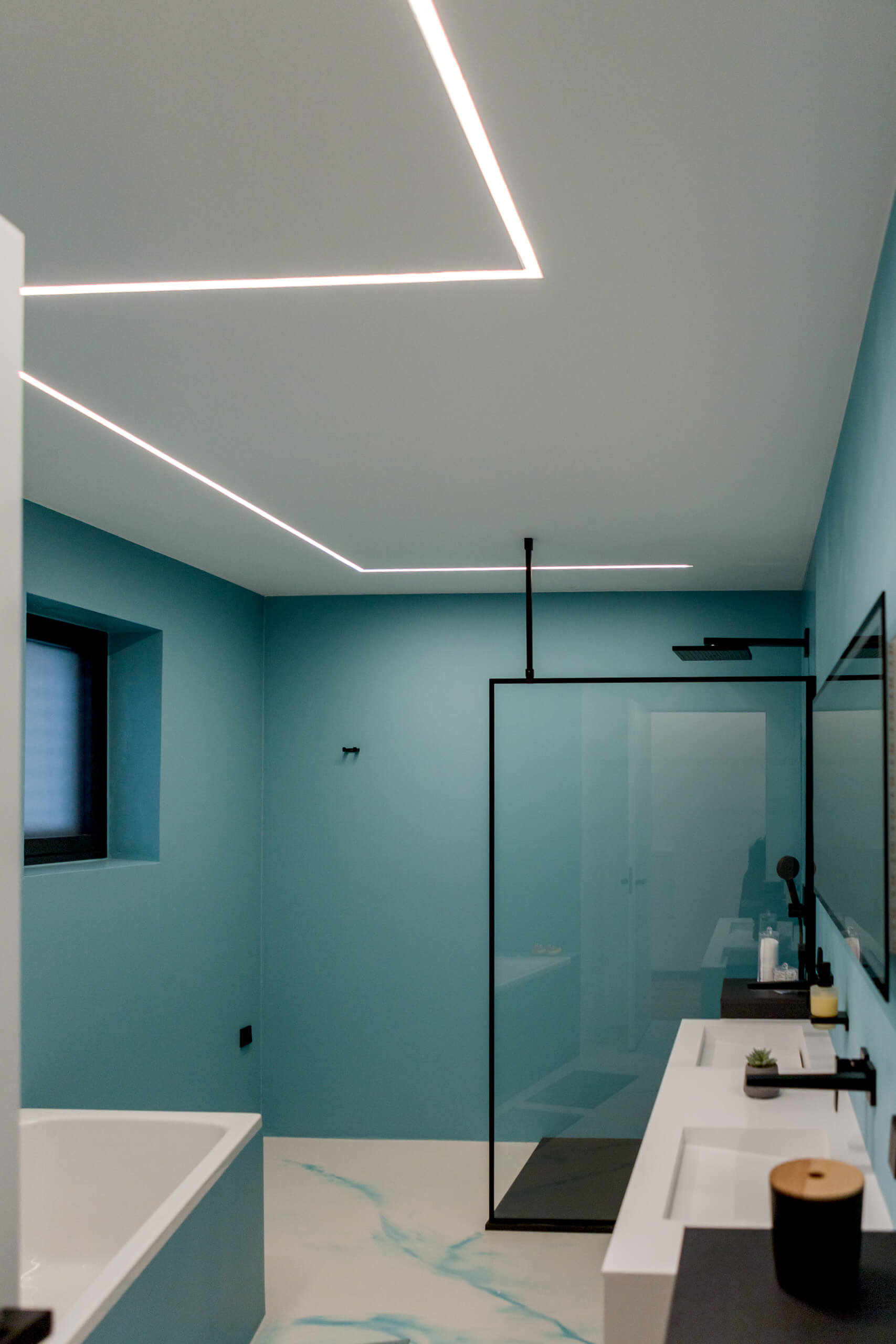 Modernes Badezimmer mit blauen Wänden, Duschkabine und Waschtisch – Lichtplanung von Illumina.