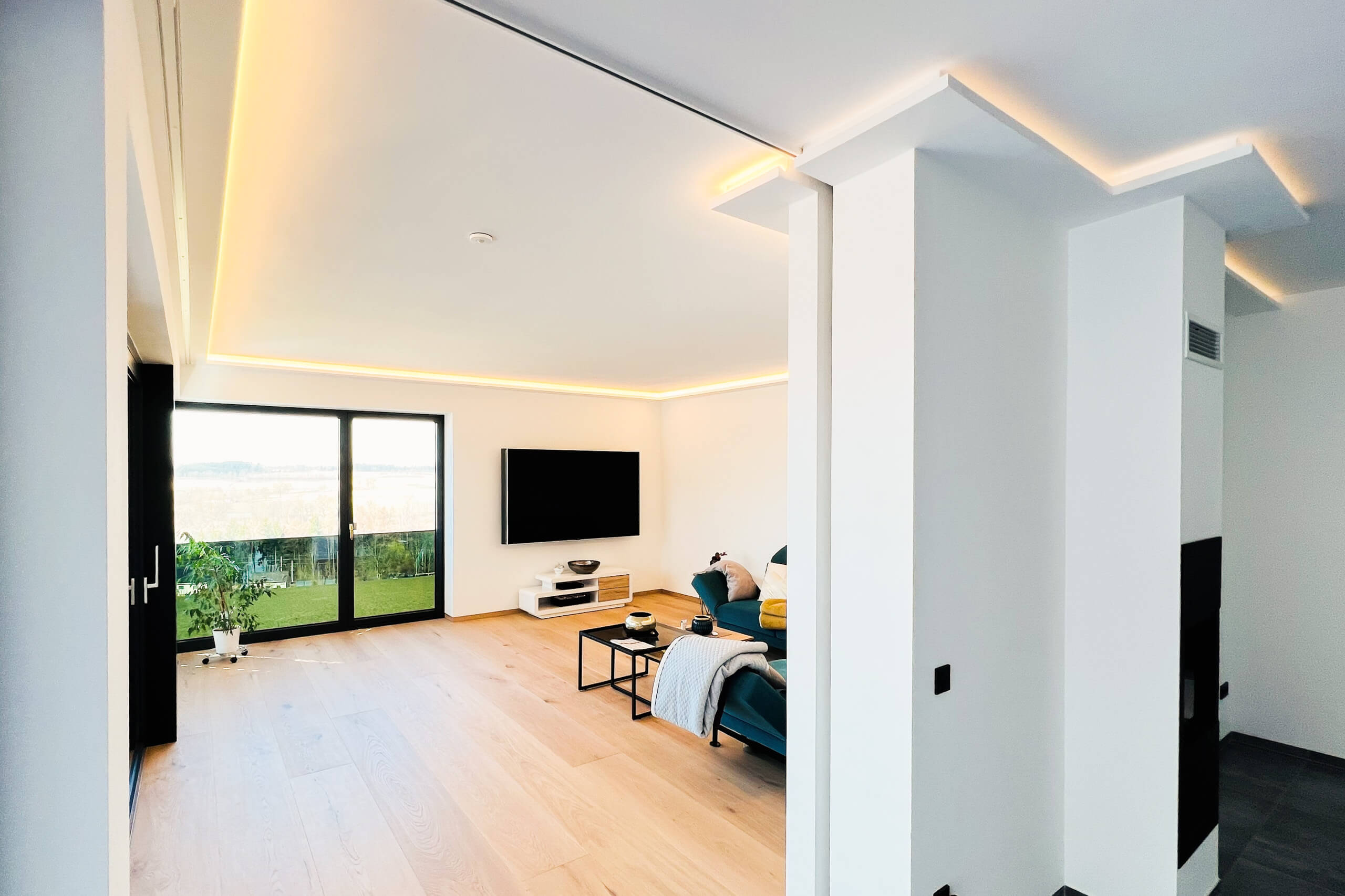 Modernes Wohnzimmer mit indirekter Beleuchtung und großem Fenster – Lichtplanung von Illumina.