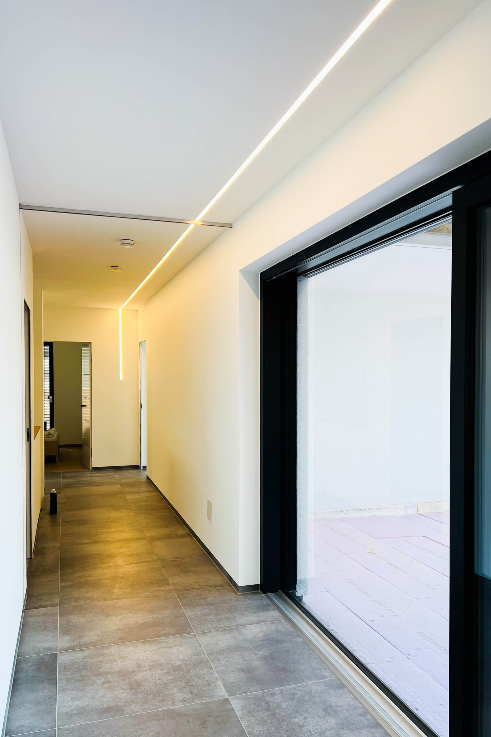 Moderner Flur mit indirekter LED-Beleuchtung und großem Glasportal
