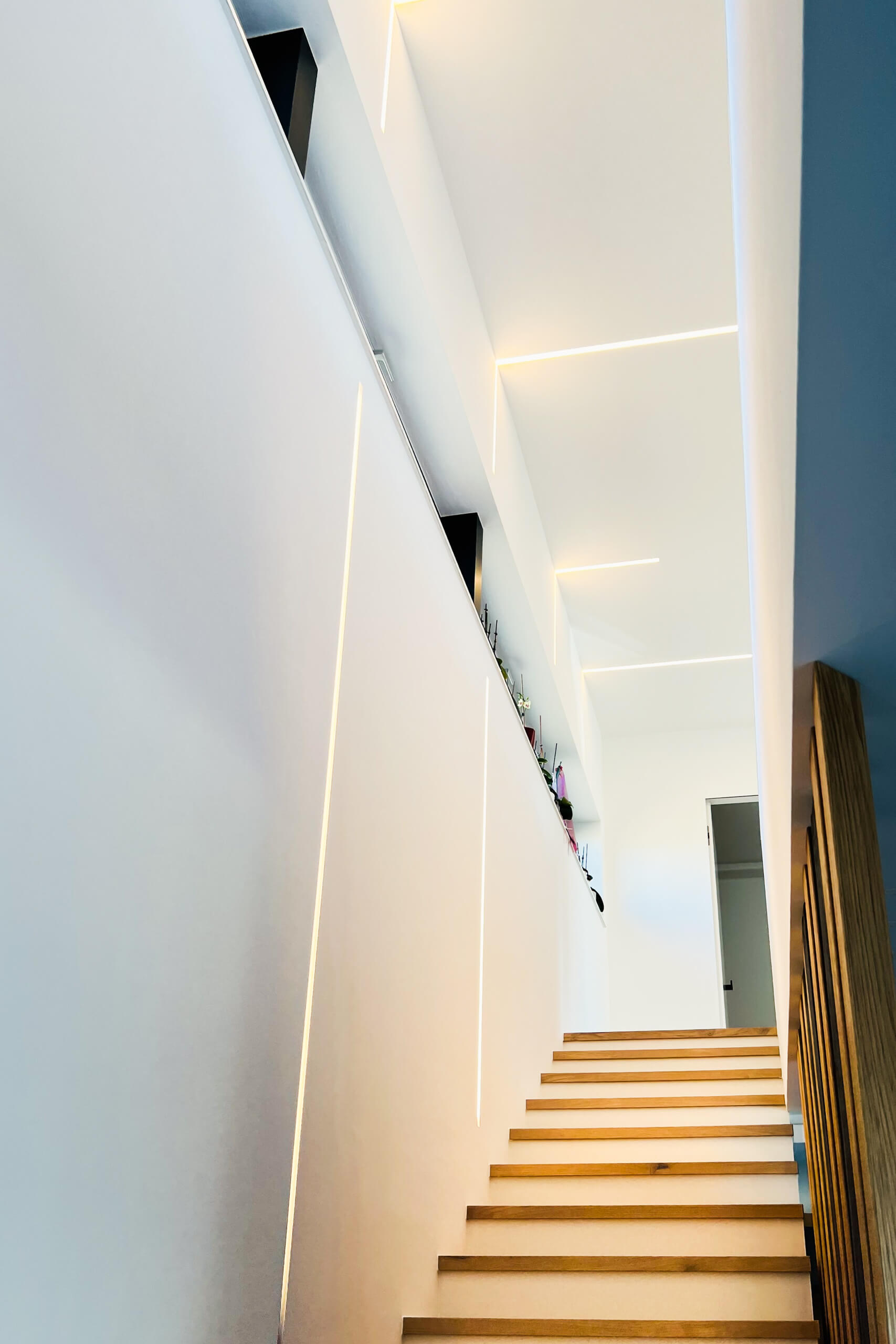 Moderne Treppe mit indirekter Beleuchtung und hölzernen Stufen, Lichtplanung von Illumina.