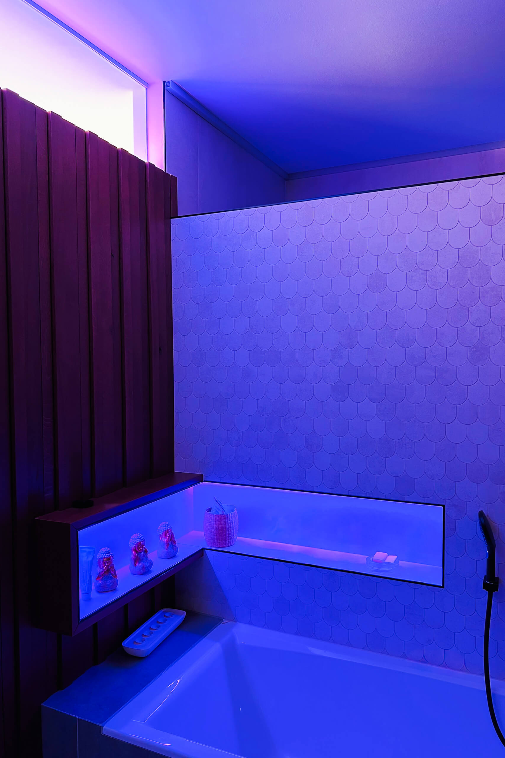 Modernes Badezimmer mit indirekter blauer Beleuchtung und schuppenförmiger Wandfliese