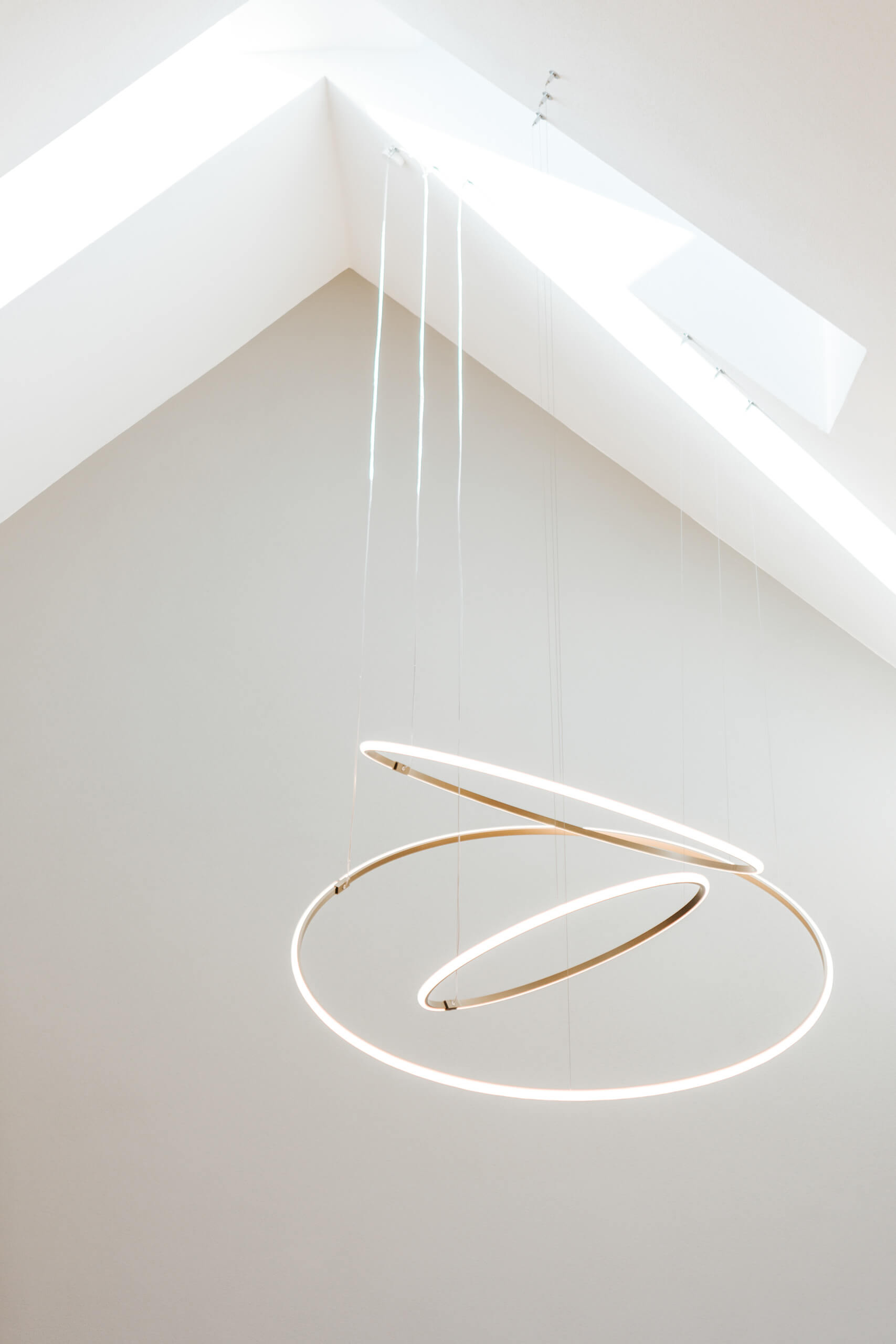 Moderne Hängeleuchte mit zwei Ringen aus warmweißem Licht im minimalistischen Raum
