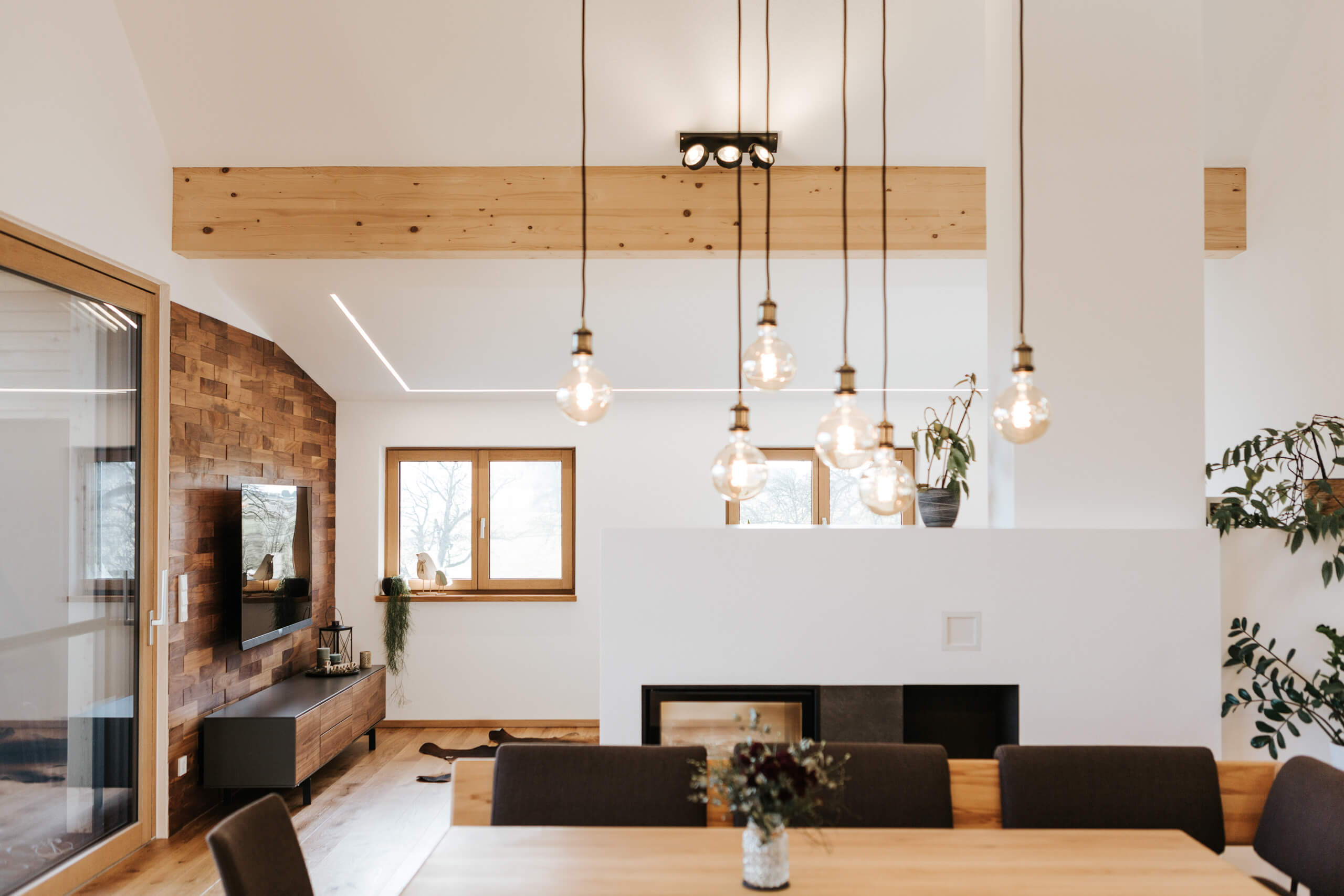 Modernes Wohnzimmer mit Kamin und Hängeleuchten – Lichtplanung von Illumina.