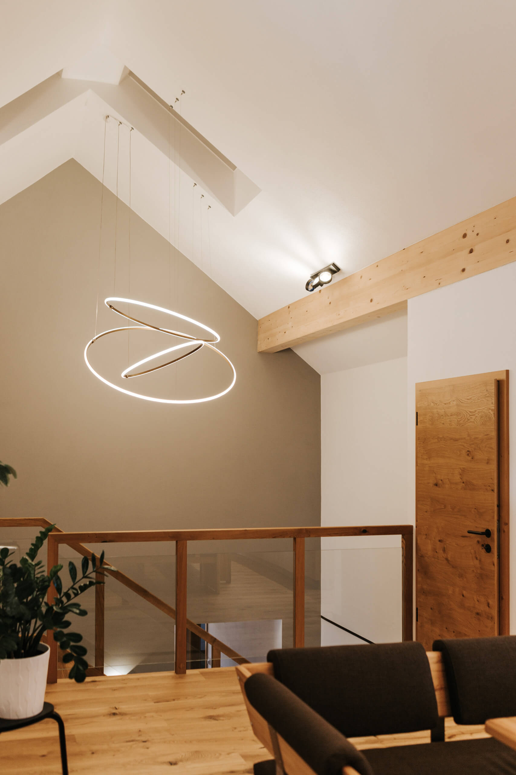 Modernes Wohnzimmer mit auffälliger Ring-Hängeleuchte und Holzdetails.