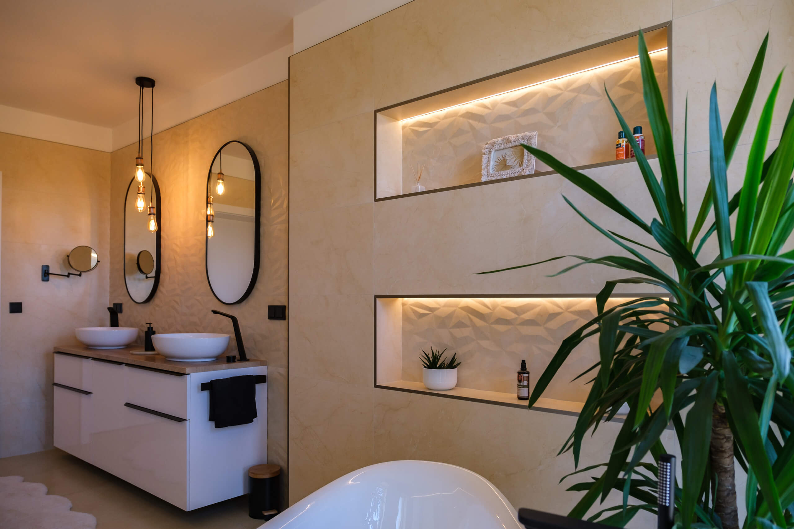 Moderne Badeinrichtung mit zwei Waschbecken, Spiegeln und eingelassenen Nischen mit Beleuchtung.