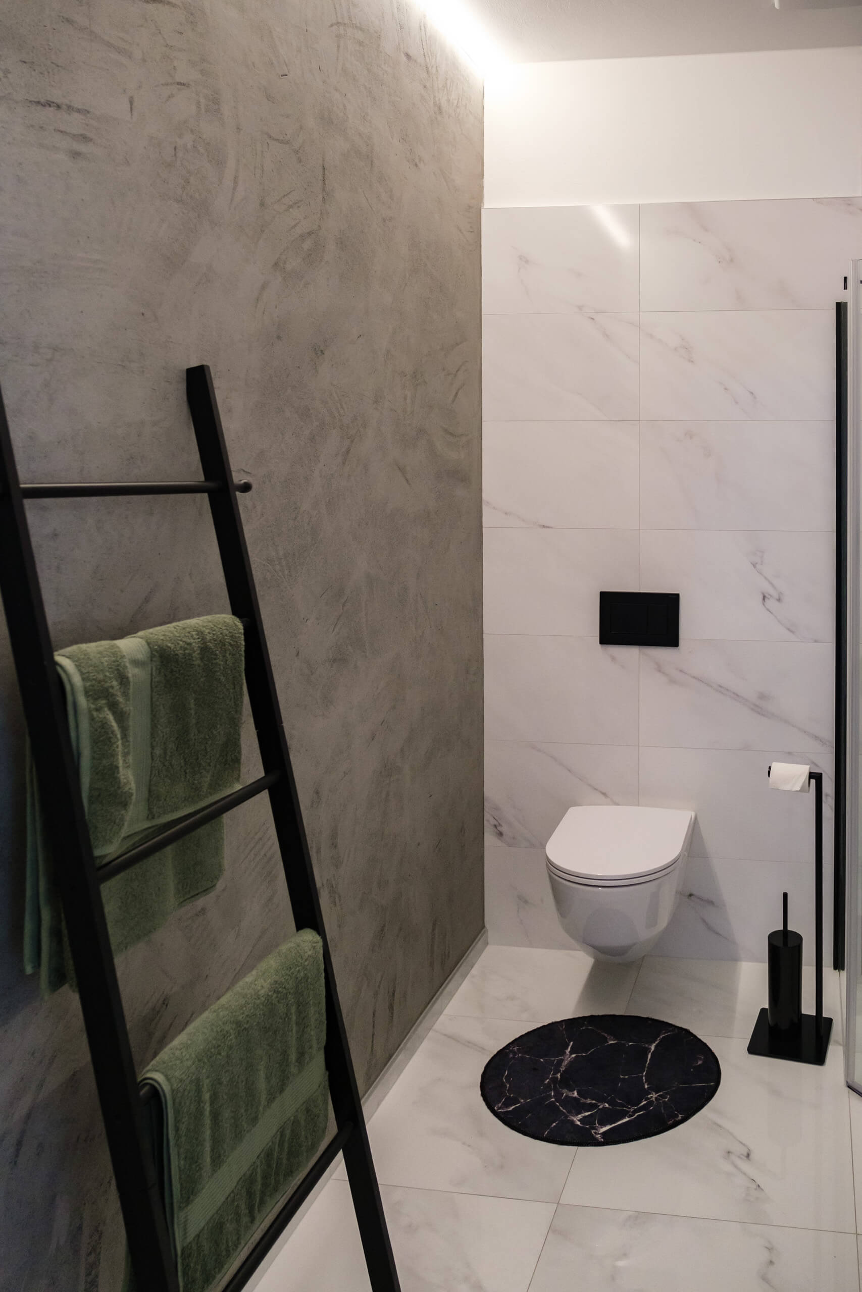 Modernes Badezimmer mit Betonwand, Leiter-Handtuchhalter und Marmorfliesen