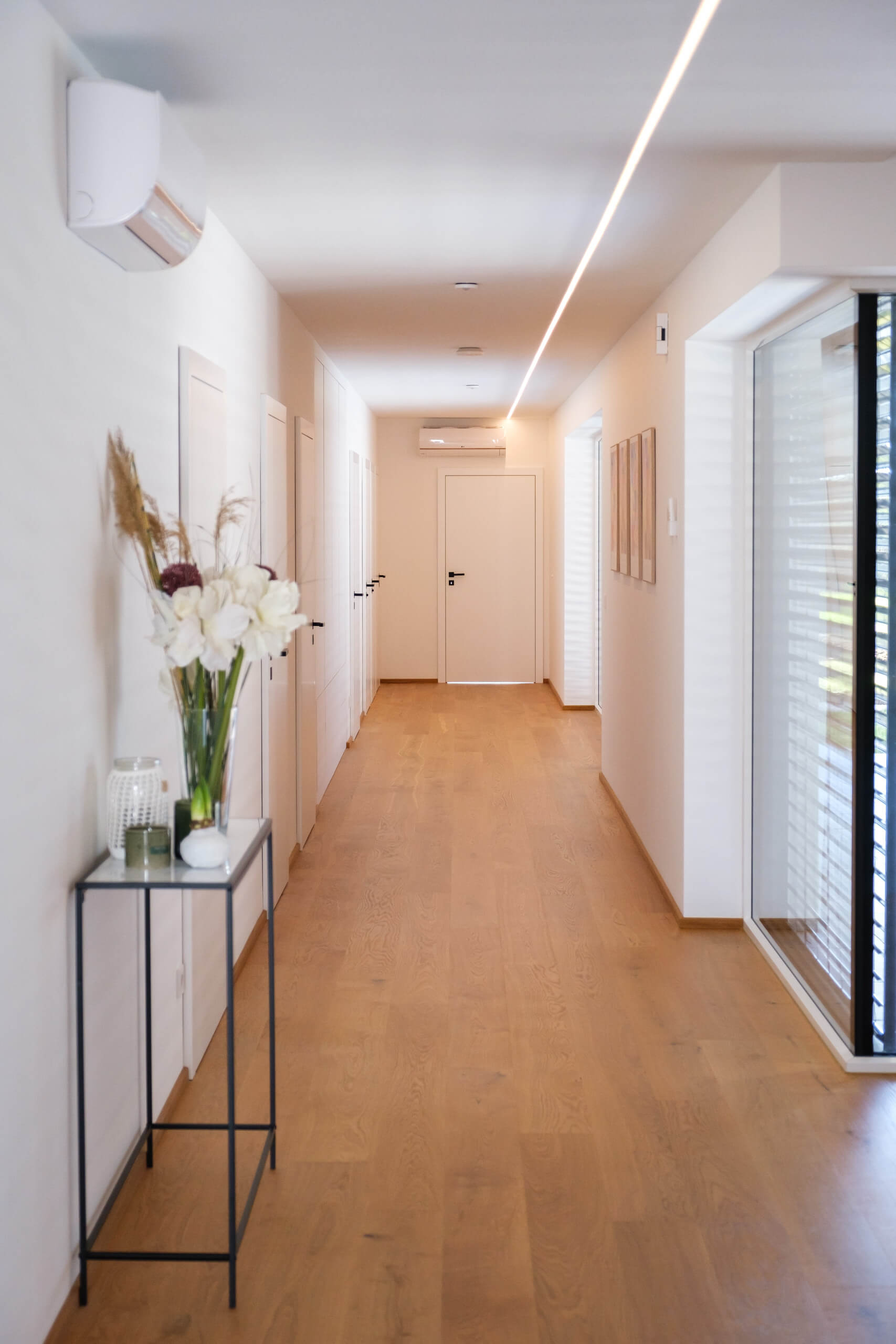 Moderner Flur mit Holzboden und indirekter Deckenbeleuchtung, Lichtplanung von Illumina.
