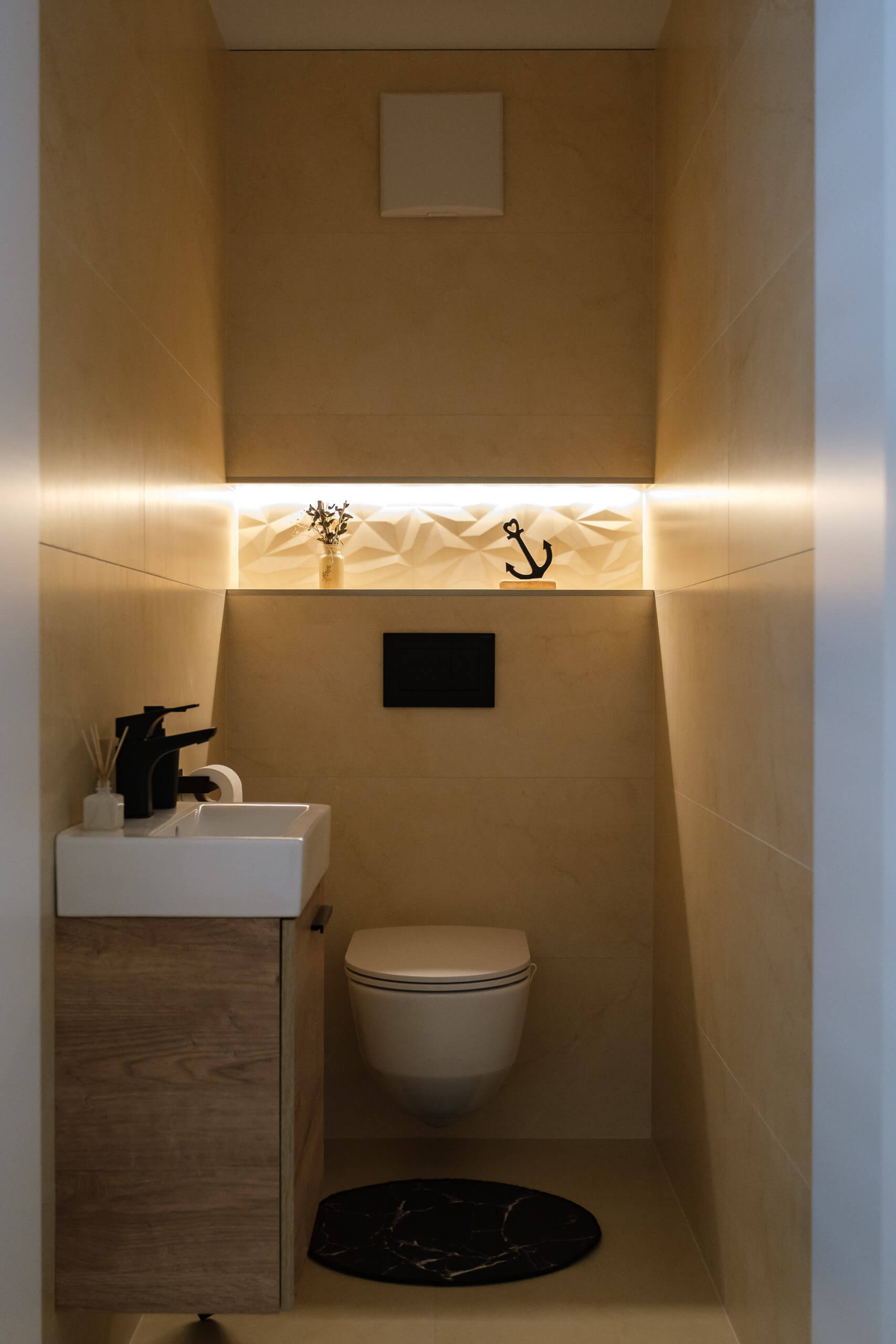 Kompaktes Gäste-WC mit Wand-WC, Waschtisch und indirekter Beleuchtung.