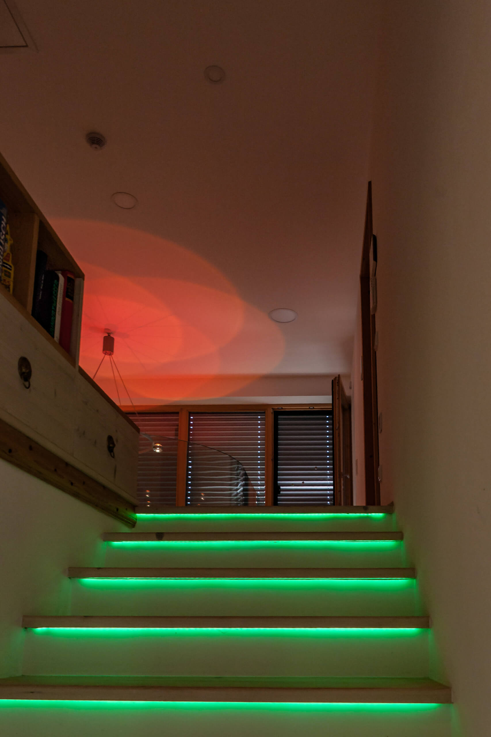 Moderne Treppe mit grüner LED-Beleuchtung und roter Akzentbeleuchtung im oberen Bereich.