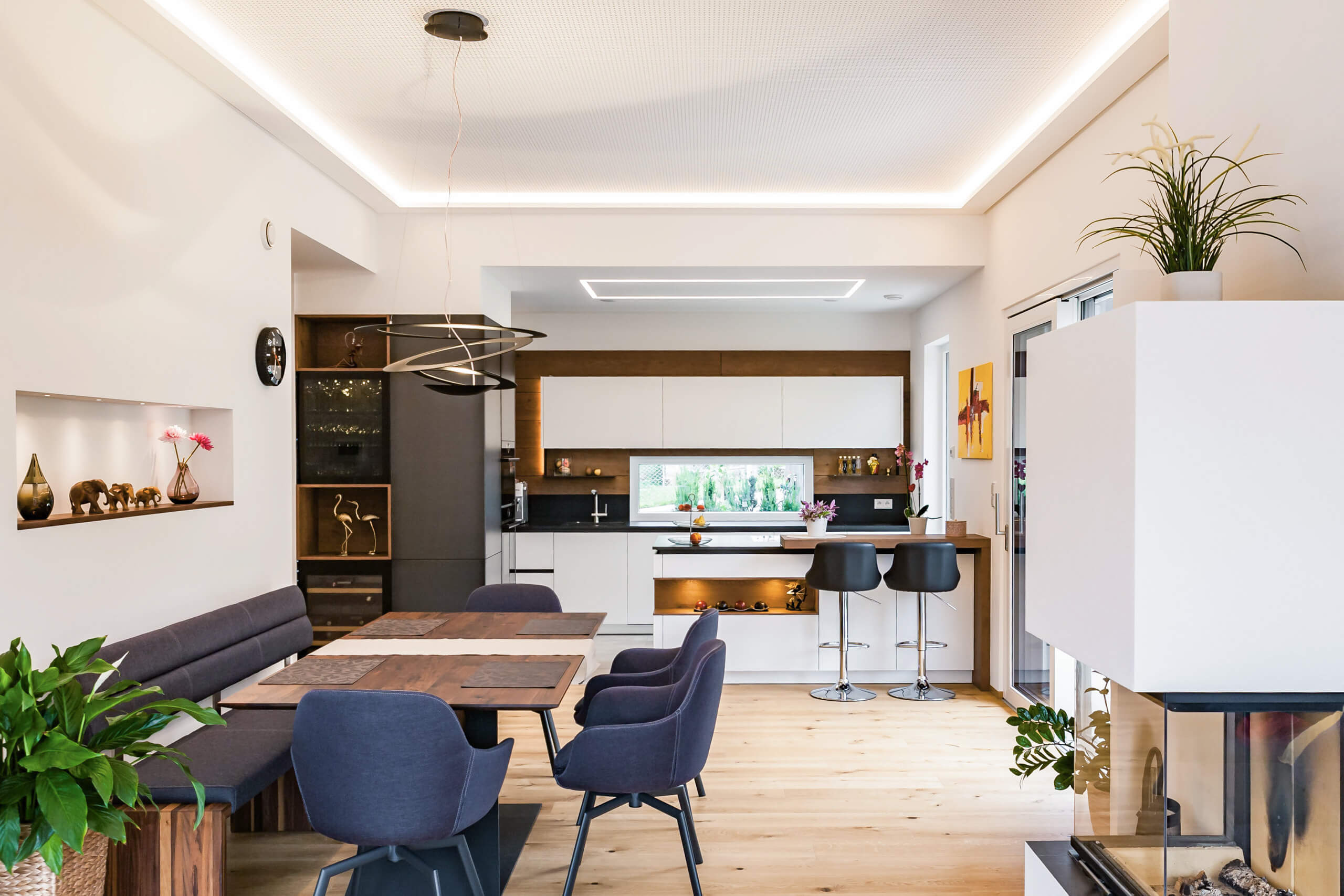 Moderne Wohnküche mit Essbereich und Kamin – Lichtplanung von Illumina.