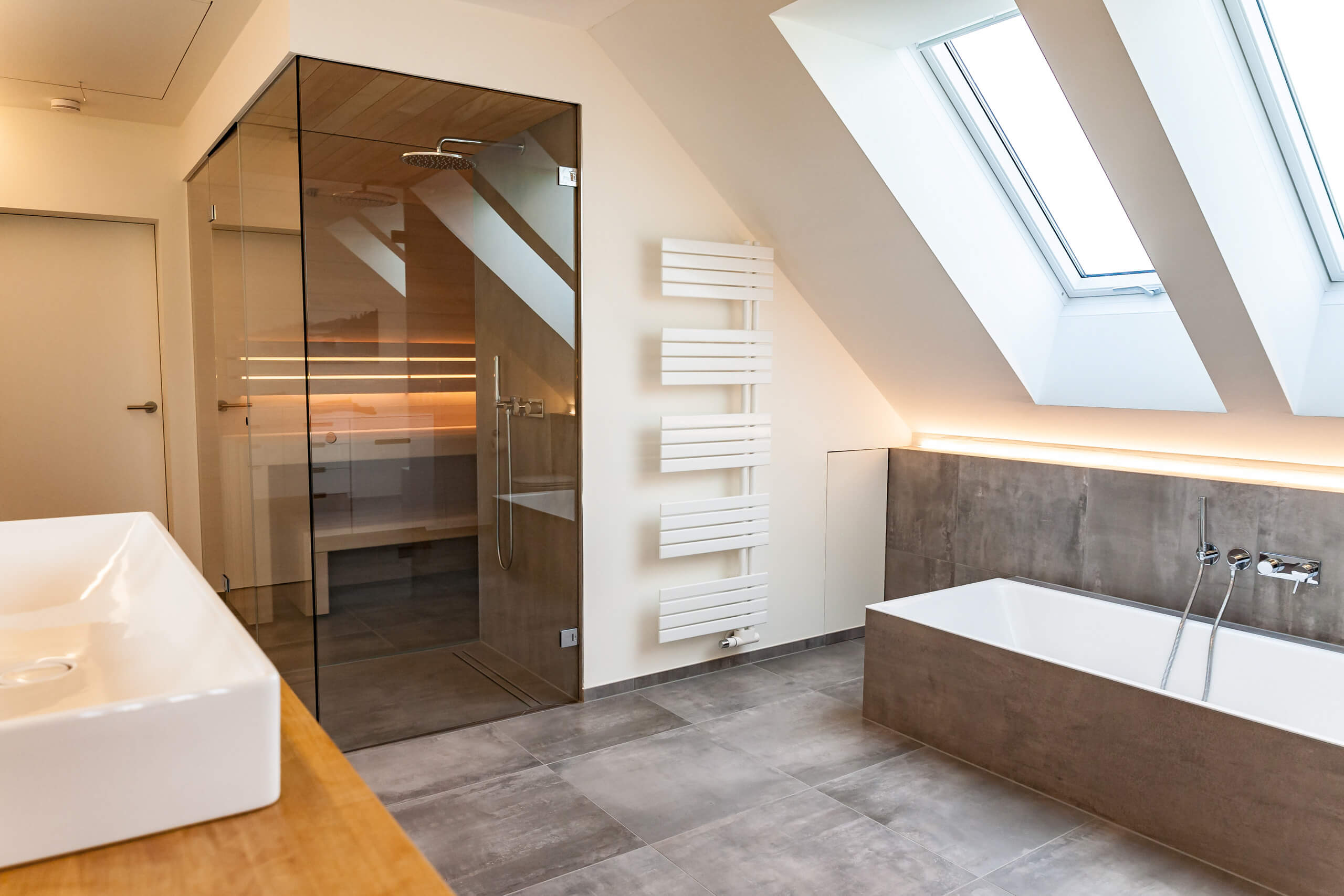 Moderne Luxus-Badezimmer mit Glas-Sauna, freistehender Badewanne und Dachfenster