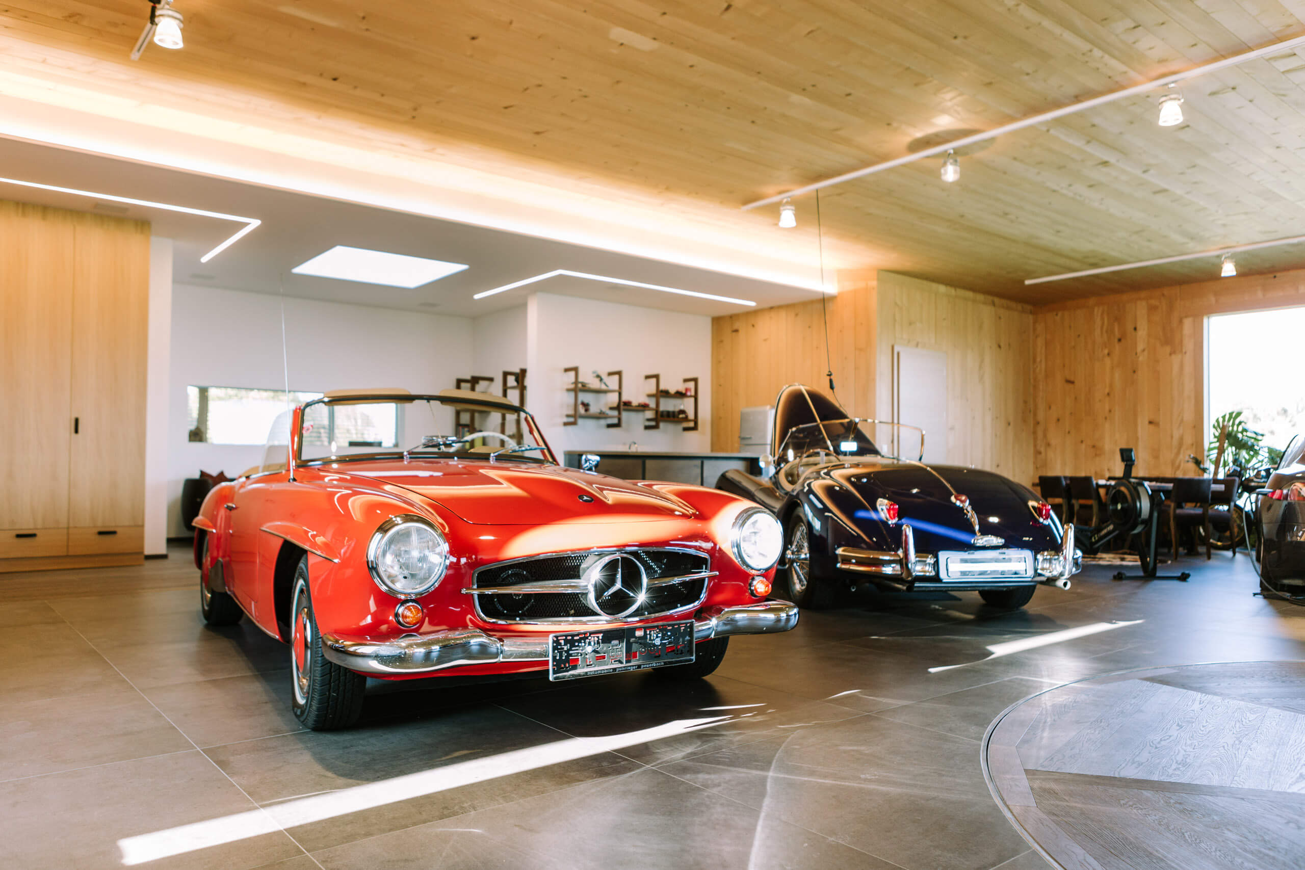 Rote und blaue Oldtimer-Cabrios in einem hellen Showroom mit Holzdecke