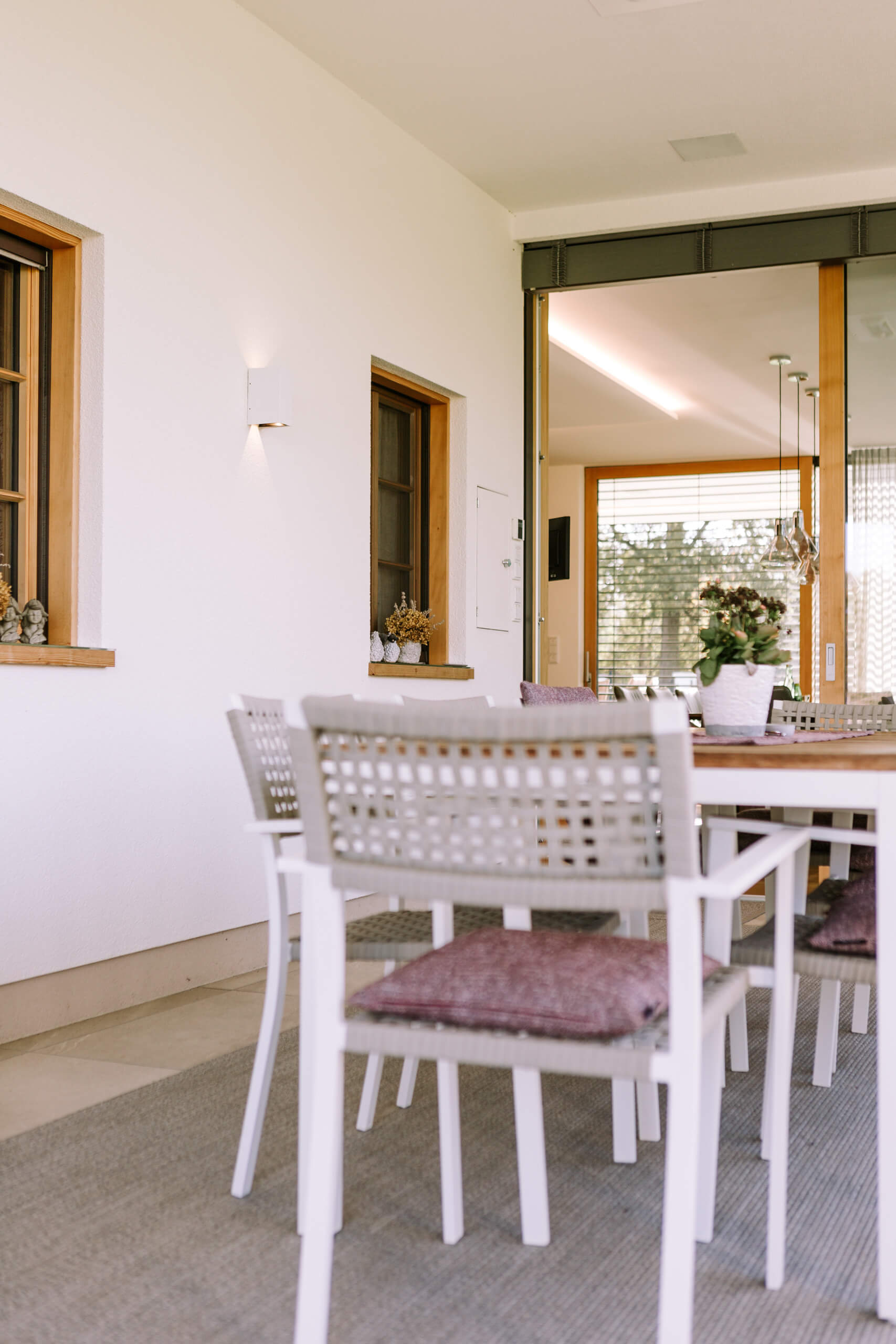 Terrasse mit Esstisch und Stühlen, beleuchtet durch dezente Wandleuchten.