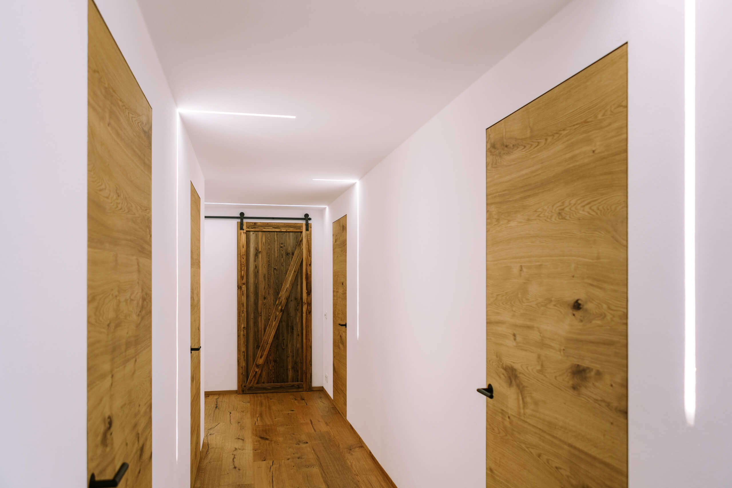 Holz-Flur mit rustikalen Türen und indirekter Beleuchtung