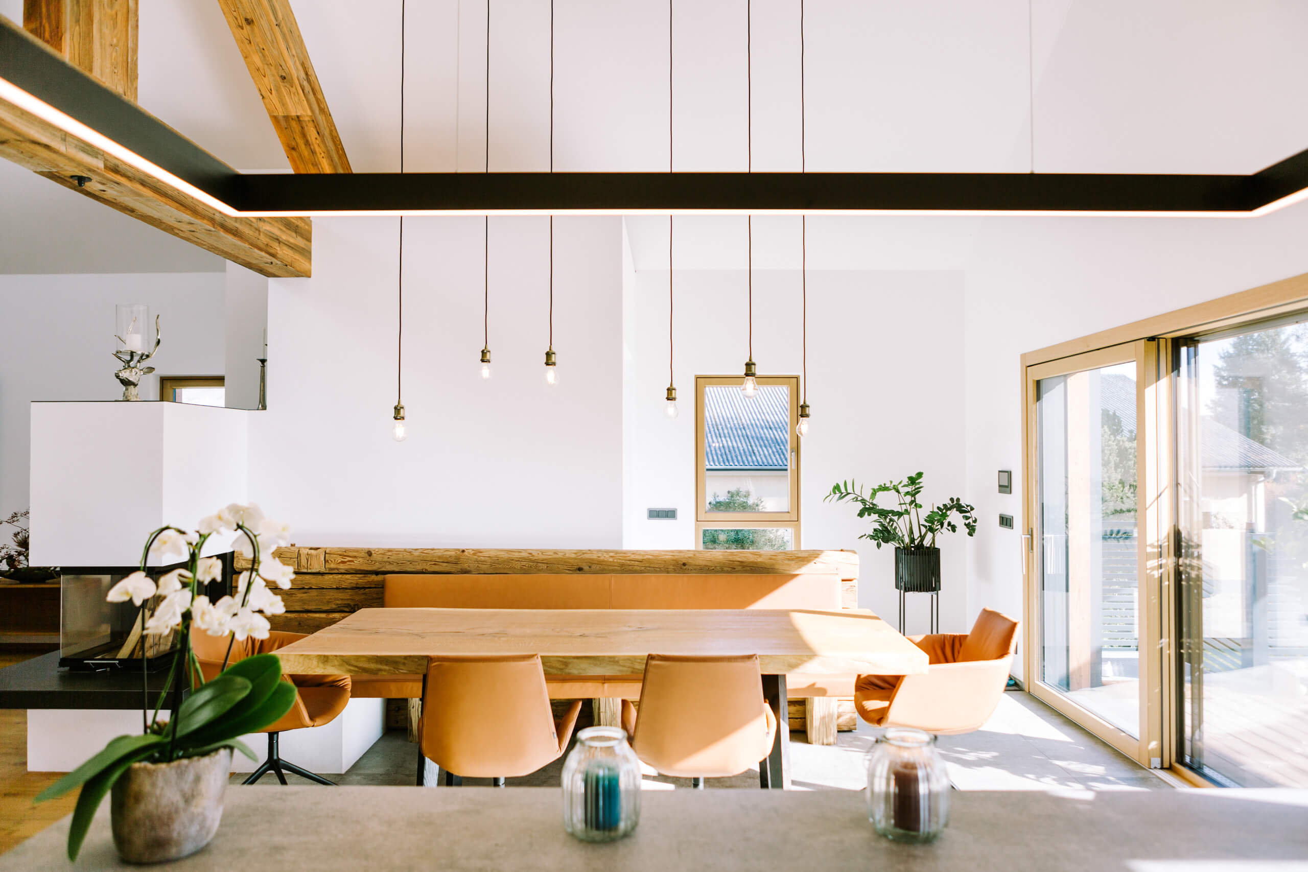 Helle Esszimmer- und Wohnküchenszene mit Holztisch, Ledersitzen und moderner Hängeleuchte.