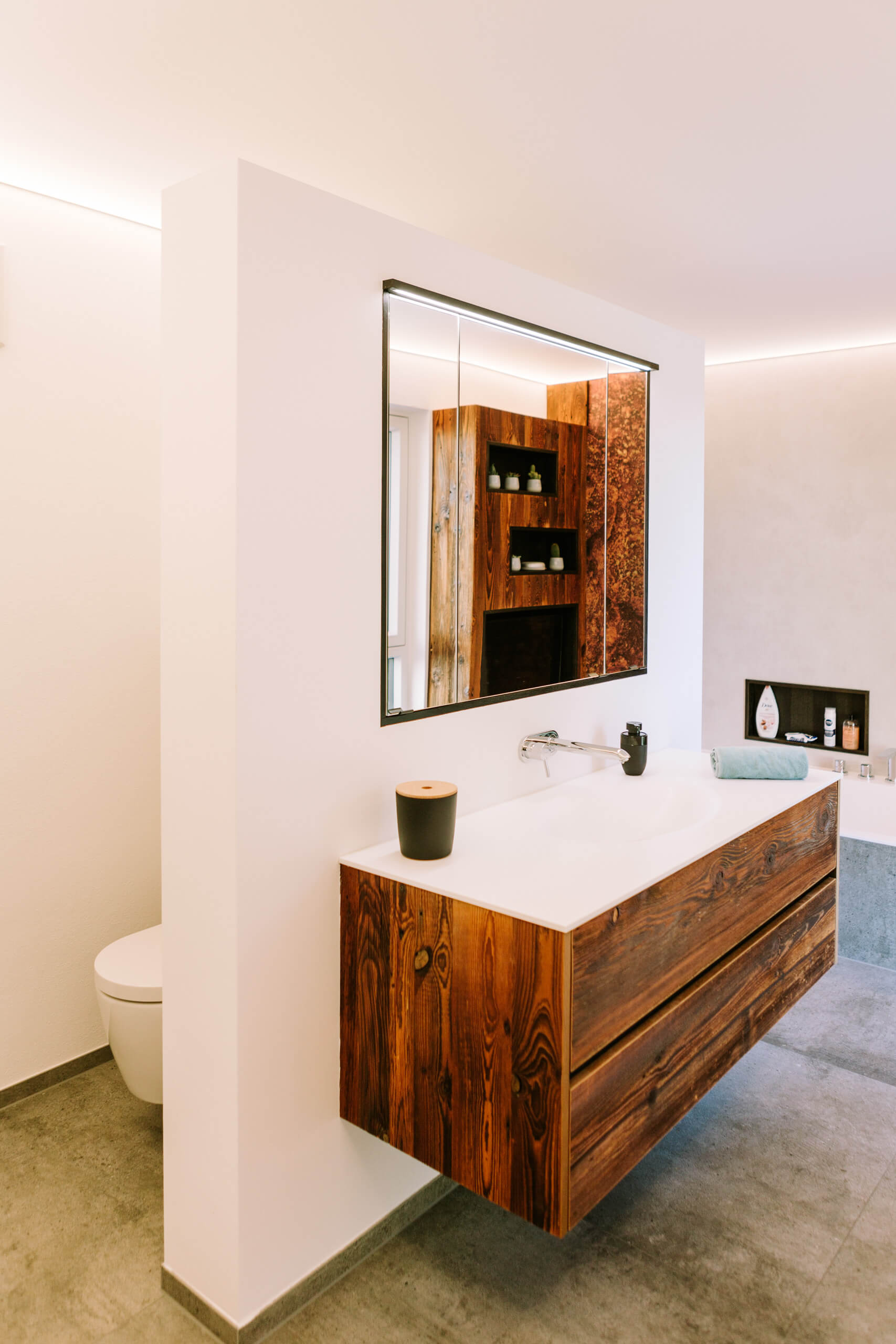 Modernes Badezimmer mit Waschtisch aus Holz und integriertem Spiegel – Lichtplanung von Illumina