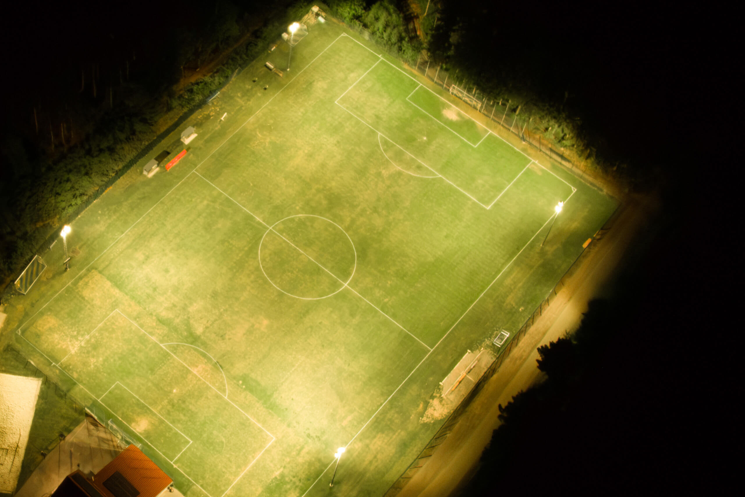 Beleuchteter Fußballplatz bei Nacht mit Flutlichtstrahlern