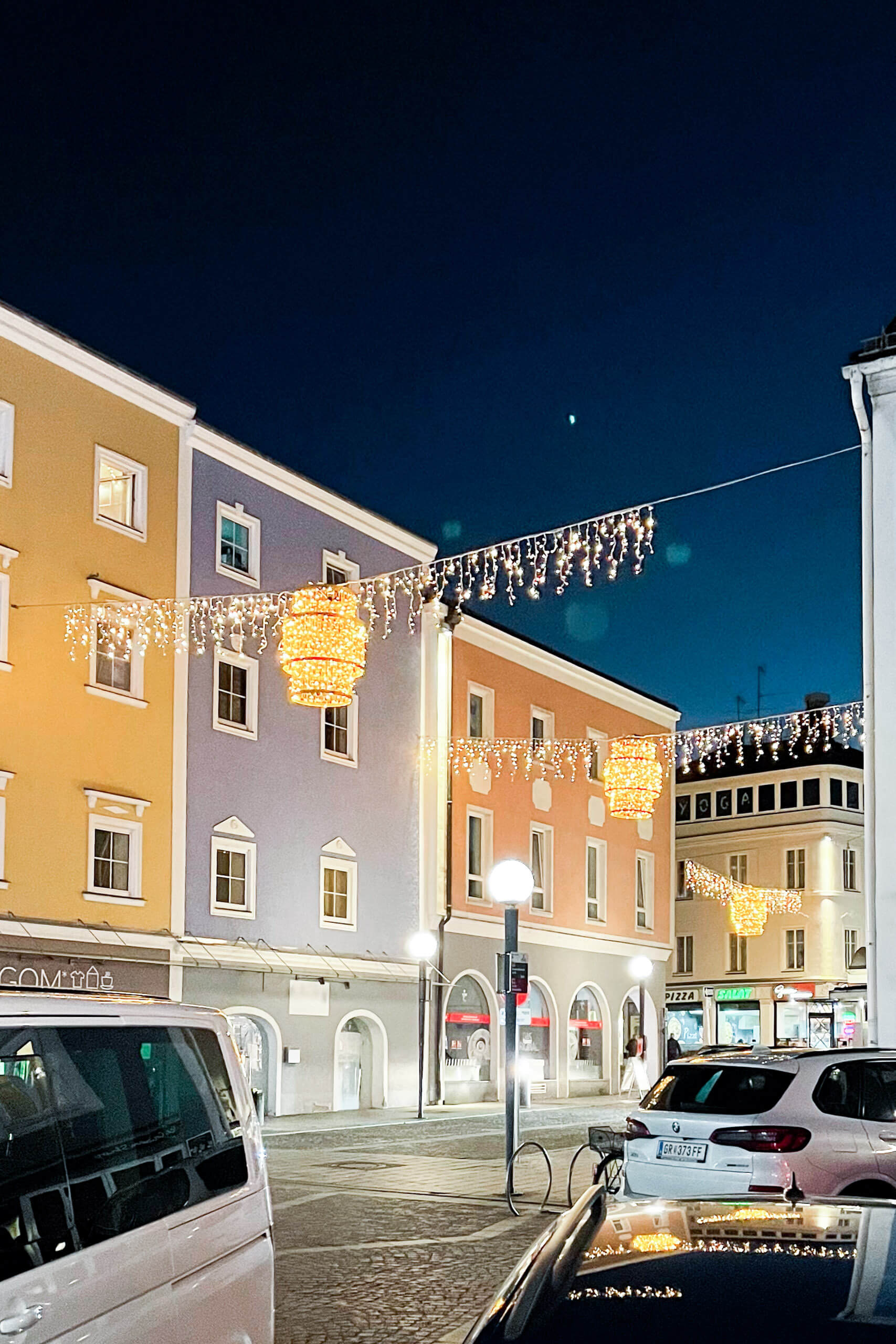 Abendliche Straßenbeleuchtung mit bunten Häusern und Lichterketten in Österreich
