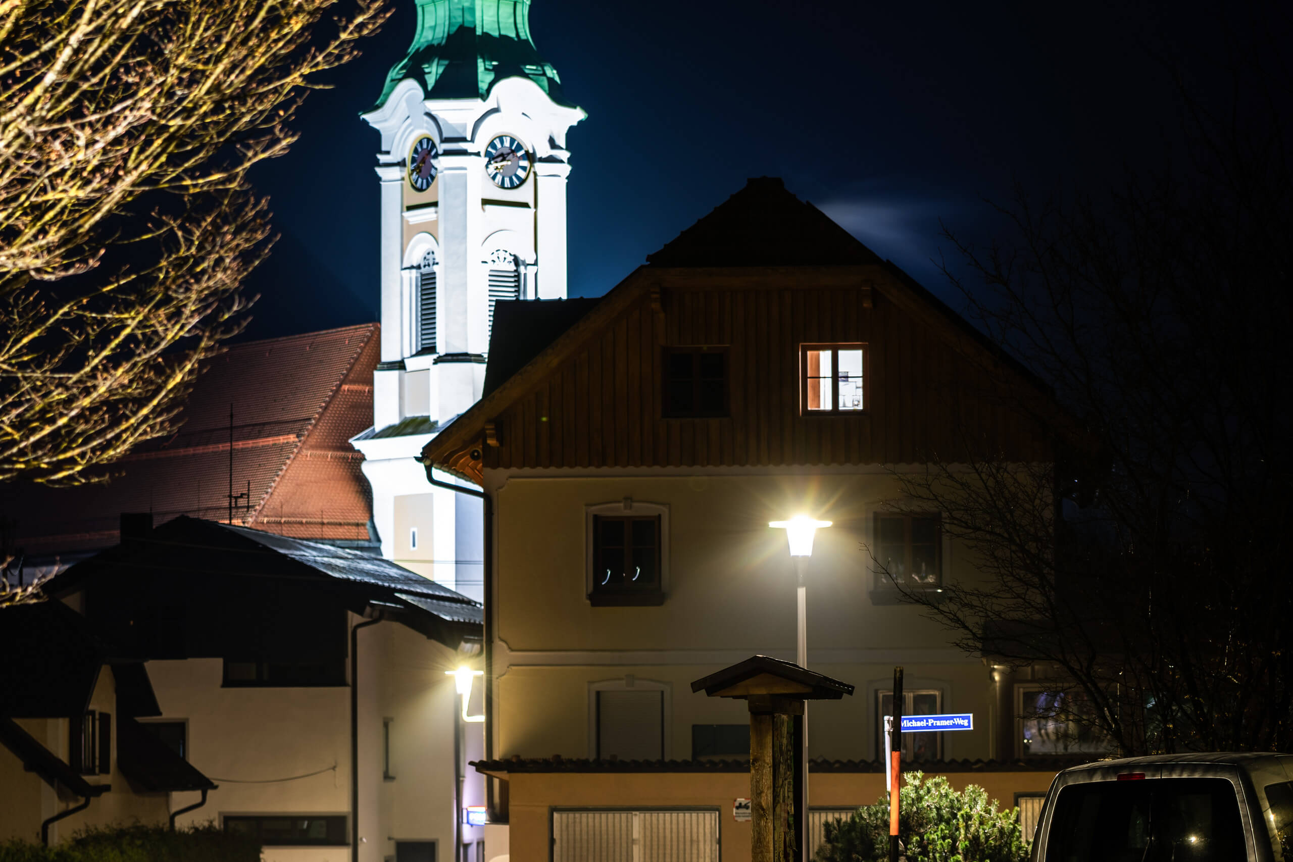 Beleuchtetes Haus mit Kirchturm im Hintergrund bei Nacht