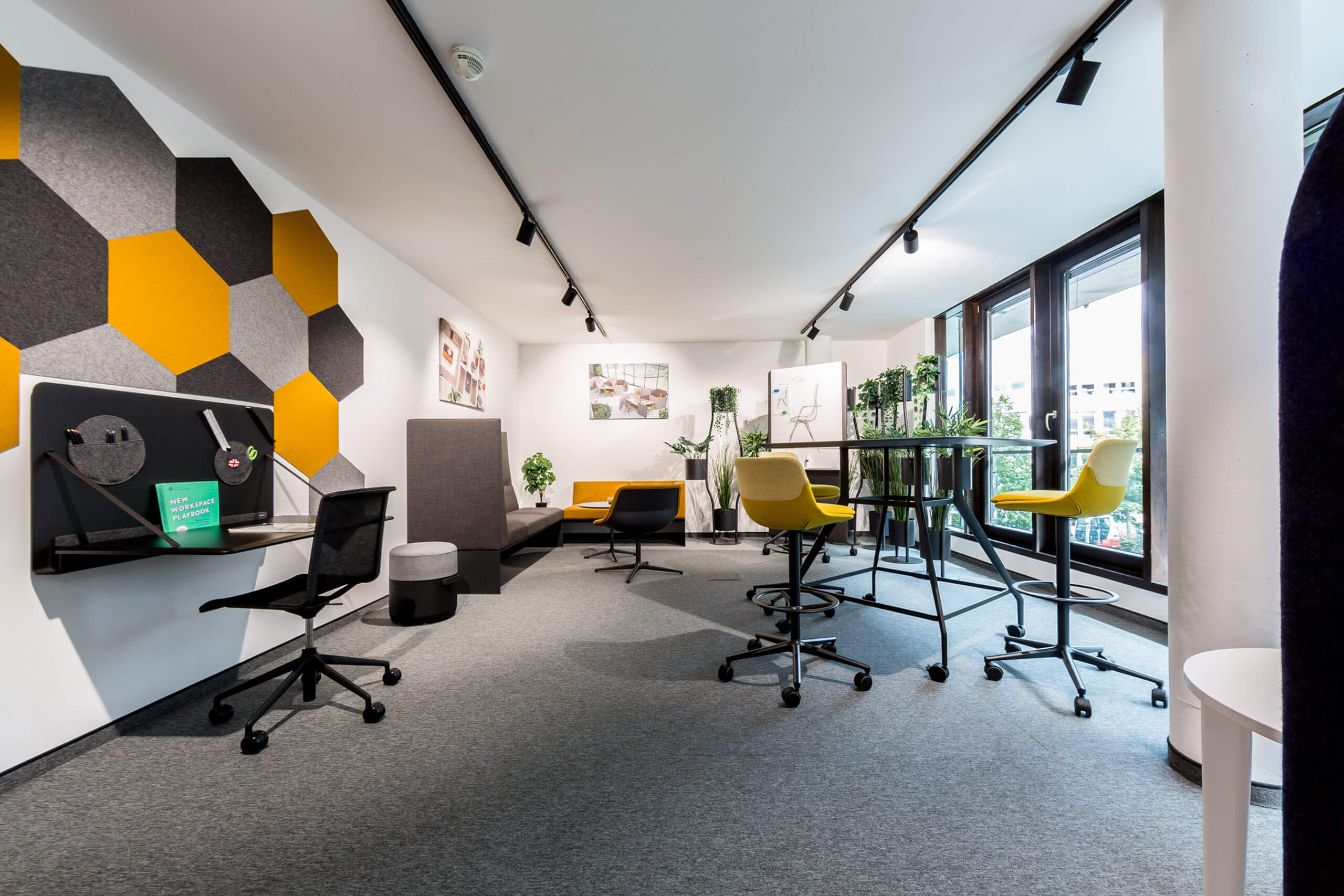 Modernes Büro mit Sitzmöbeln, Stehtischen und Wandgestaltung – Lichtplanung von Illumina.