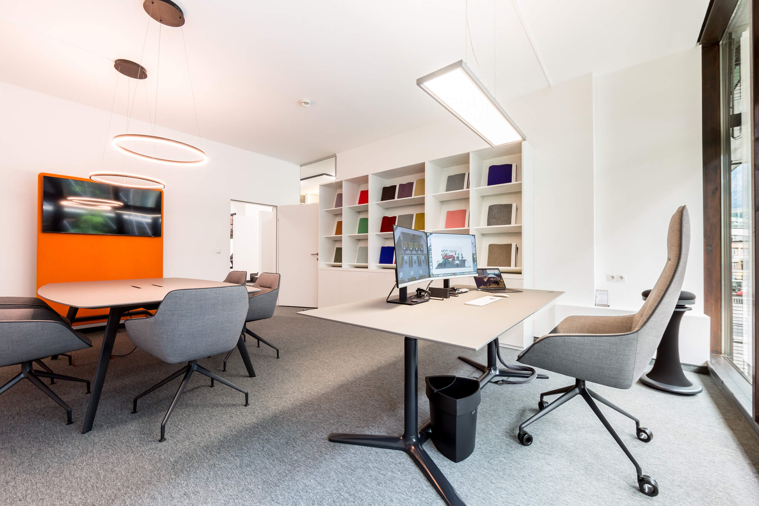 Modernes Büro mit Konferenztisch, Bürostühlen und Wandregalen – Lichtplanung von Illumina.