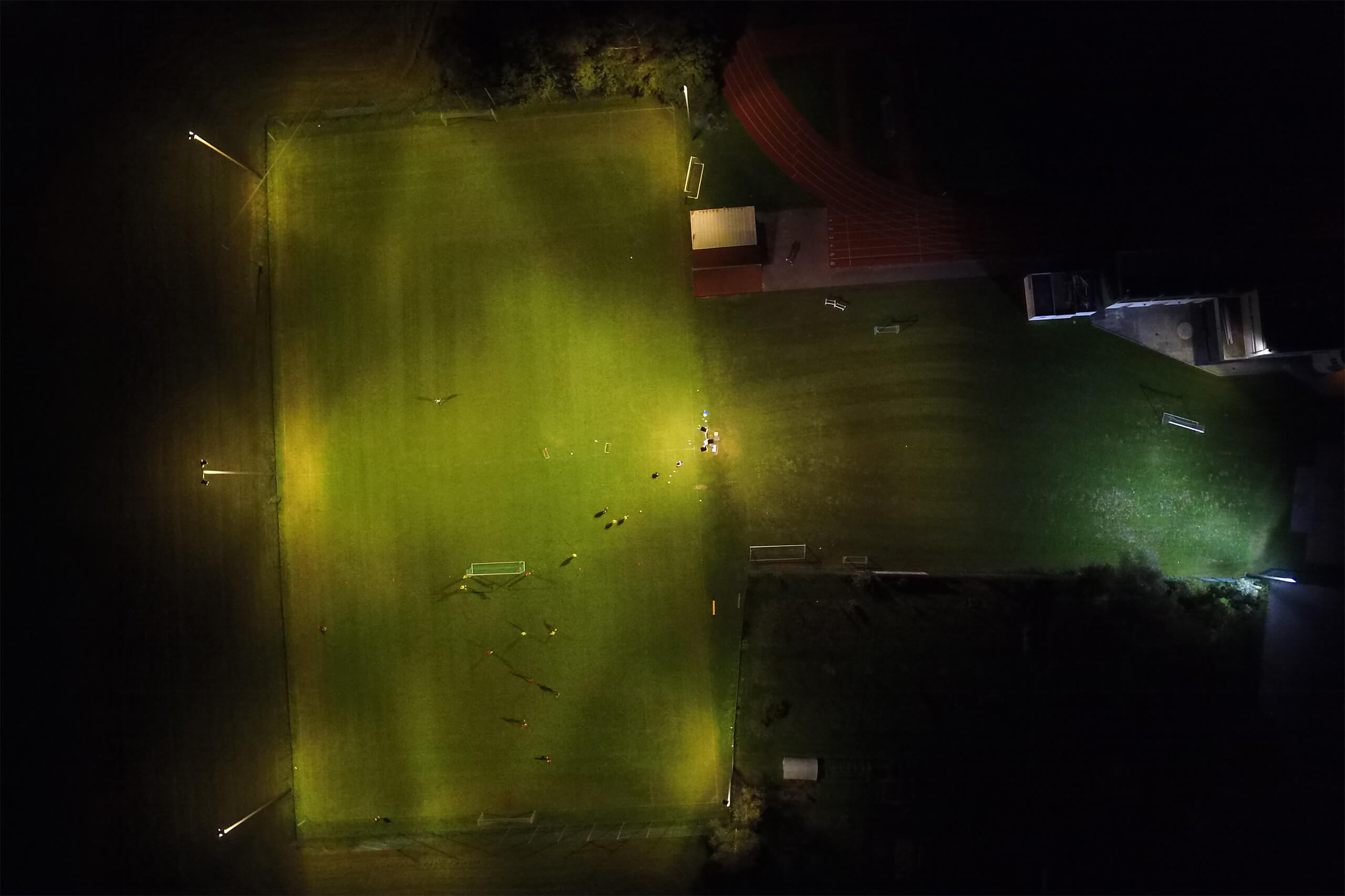Sportplatzbeleuchtung mit heller, gleichmäßiger Ausleuchtung durch Mastleuchten bei Nacht.