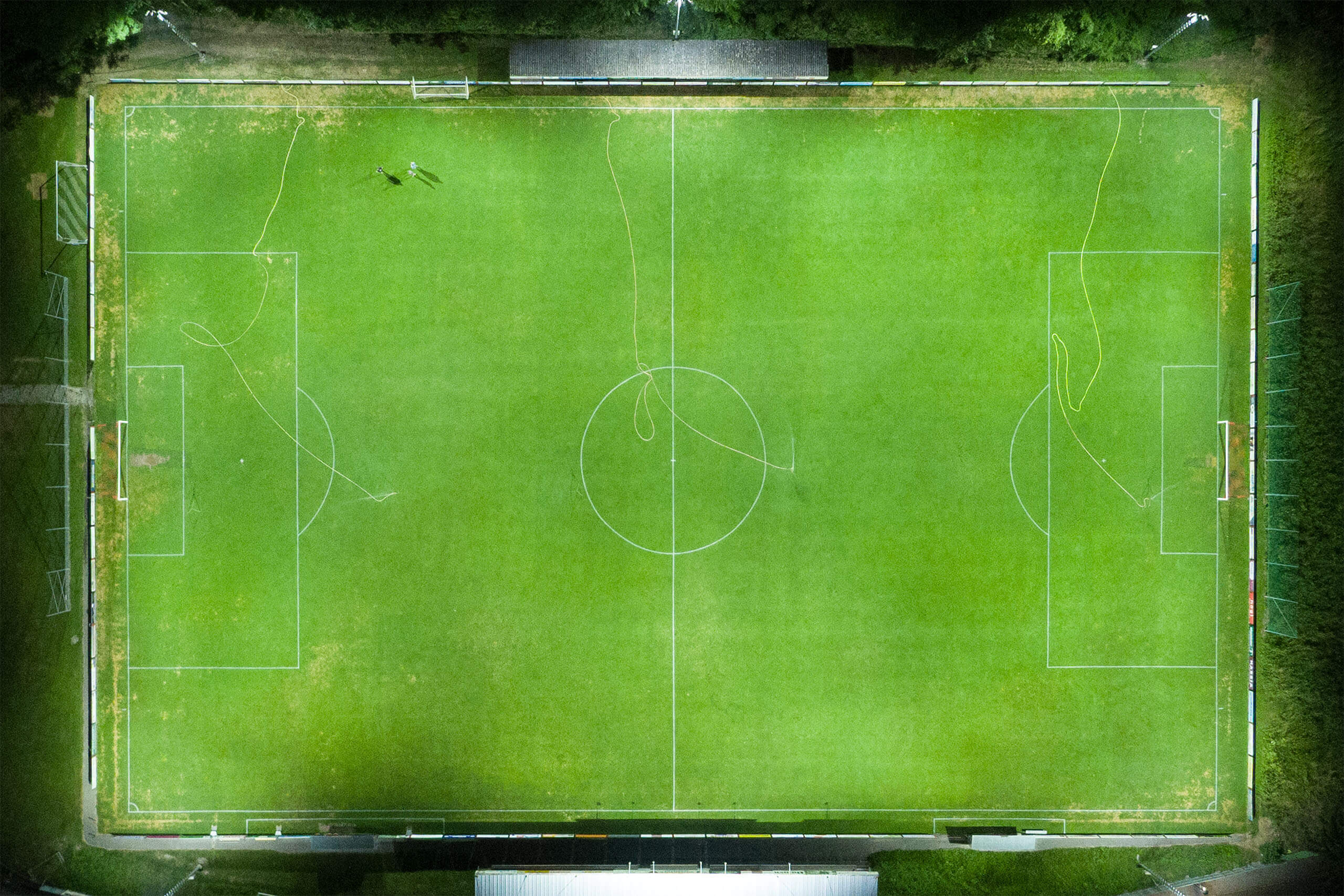 Fußballfeld bei Nacht mit Rasensprengern und Spielfeldmarkierungen und Beleuchtung von Illumina