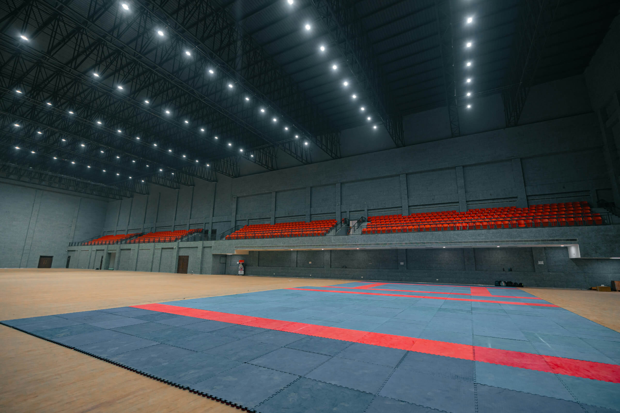 Große Sporthalle mit Tribünen und Sportfeld, beleuchtet durch moderne Hallenleuchten