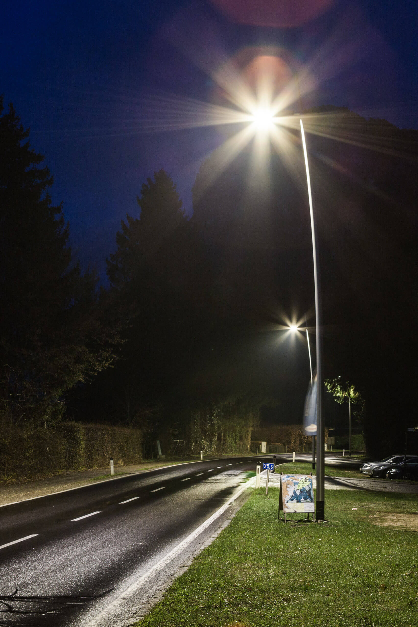 Straßenbeleuchtung bei Nacht mit hellem Lichtkegel auf nassem Asphalt.