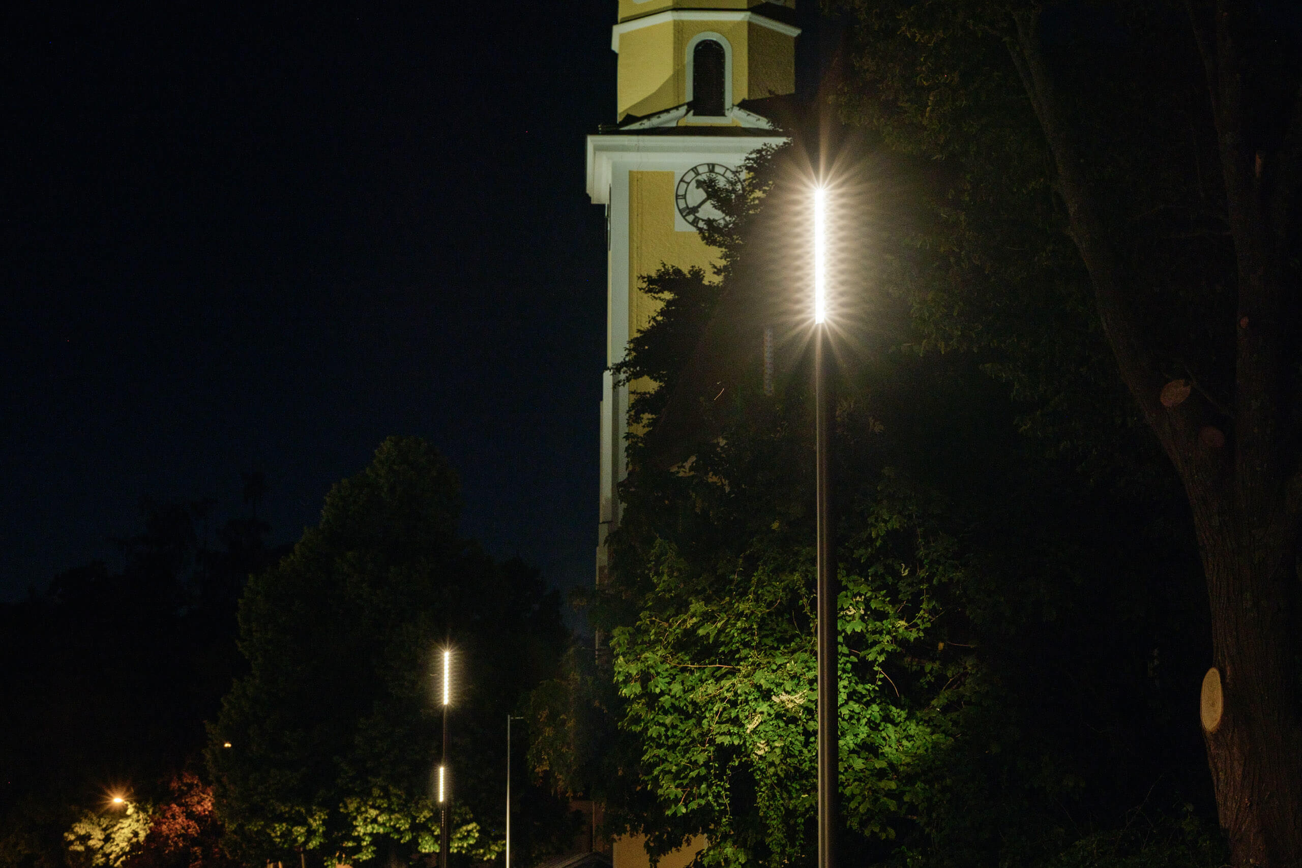 Illuminas Lichtplanung: Kirchturm mit moderner Straßenbeleuchtung bei Nacht.